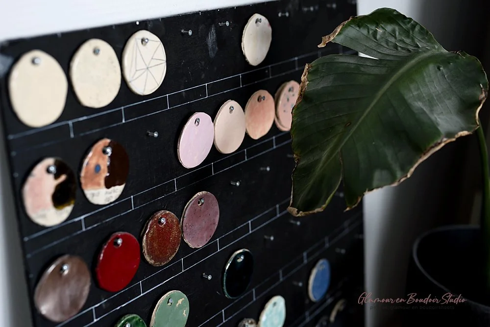 Collection of colorful paint swatches on a black display board, with a large green leaf partially covering the right side of the board.