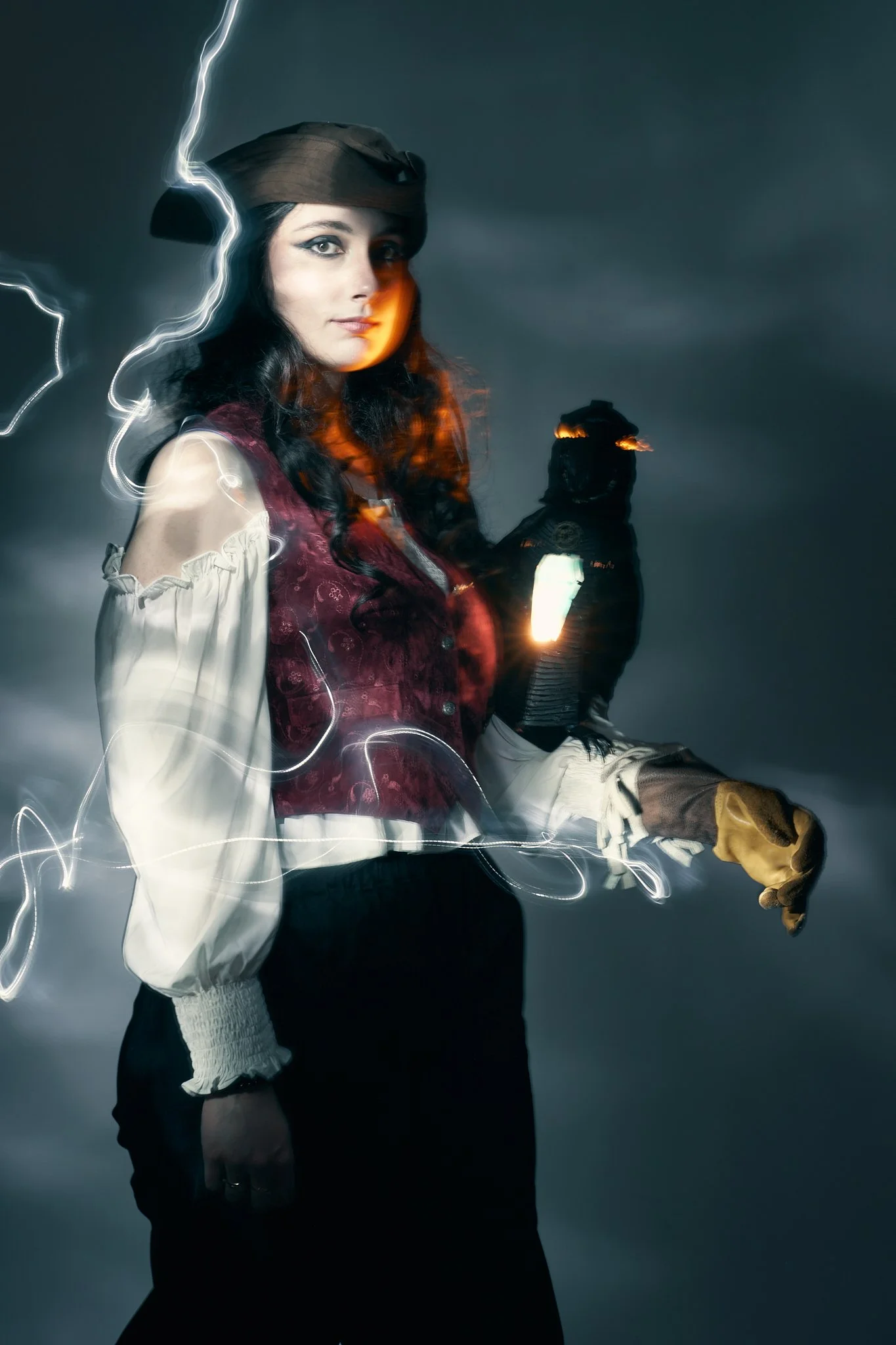 Painterly cosplay portrait of a female pirate holding a glowing-eyed raven on a gloved hand, with light-painting streaks across a stormy backdrop. Photographed by Simon Rogghe.