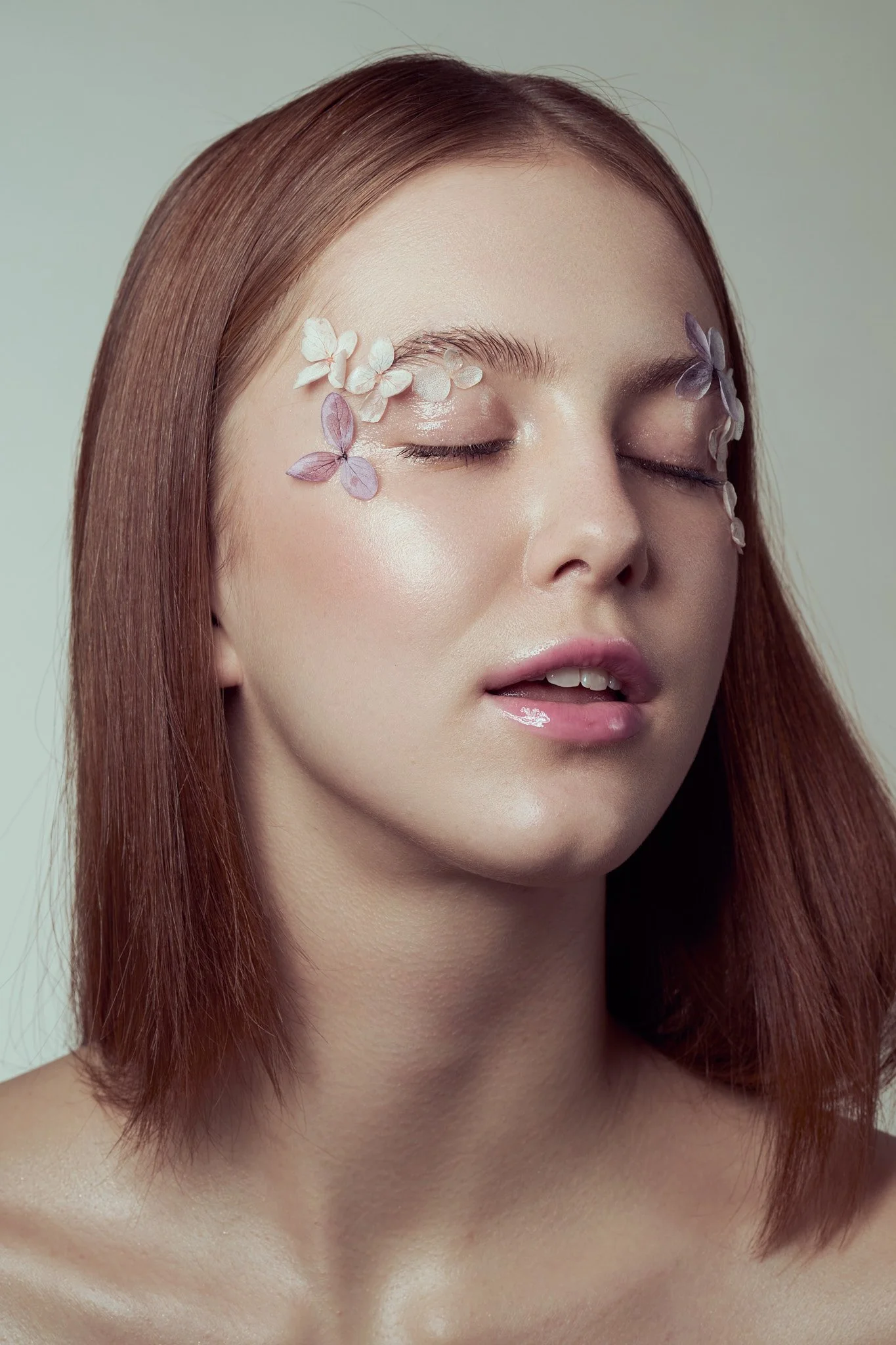 Beauty close-up portrait of a red-haired woman with small 3D butterfly appliqués around her eyes.