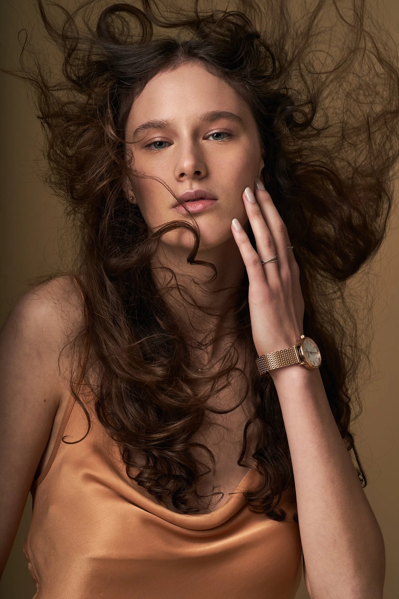 Portrait mode capturant un mouvement naturel dans les cheveux, avec des tons dorés et un look décontracté mais élégant — idéal pour une campagne de bijoux.