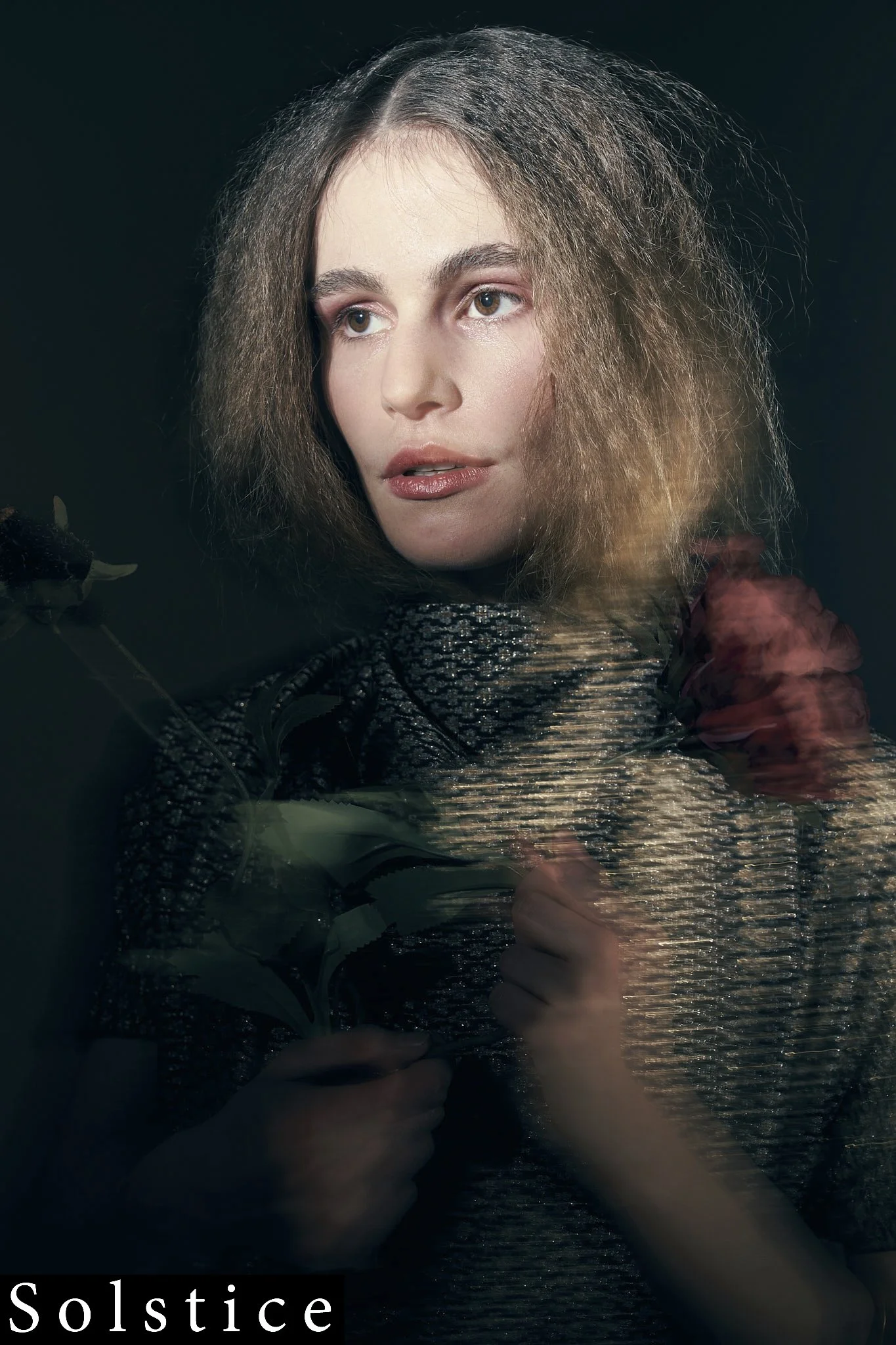 Dark editorial portrait with motion blur effect, female model holding dark red roses against black background, atmospheric fashion photography by Simon Rogghe, Belgian fashion photographer, Solstice Magazine