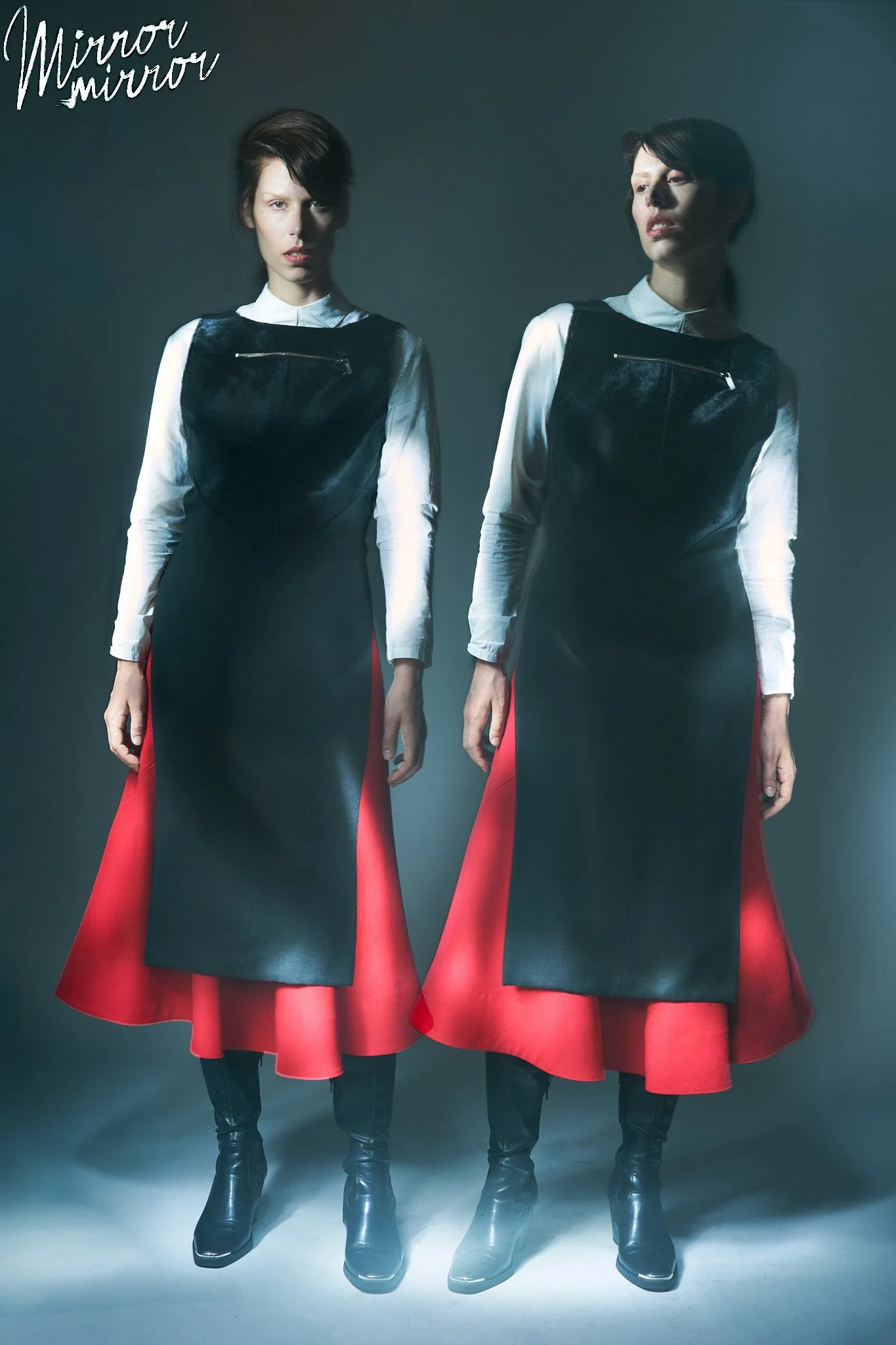 Fashion editorial portrait of a model in a black structured dress layered over a white shirt with a flowing red skirt, photographed with creative double exposure lighting by a Belgian fashion photographer.
