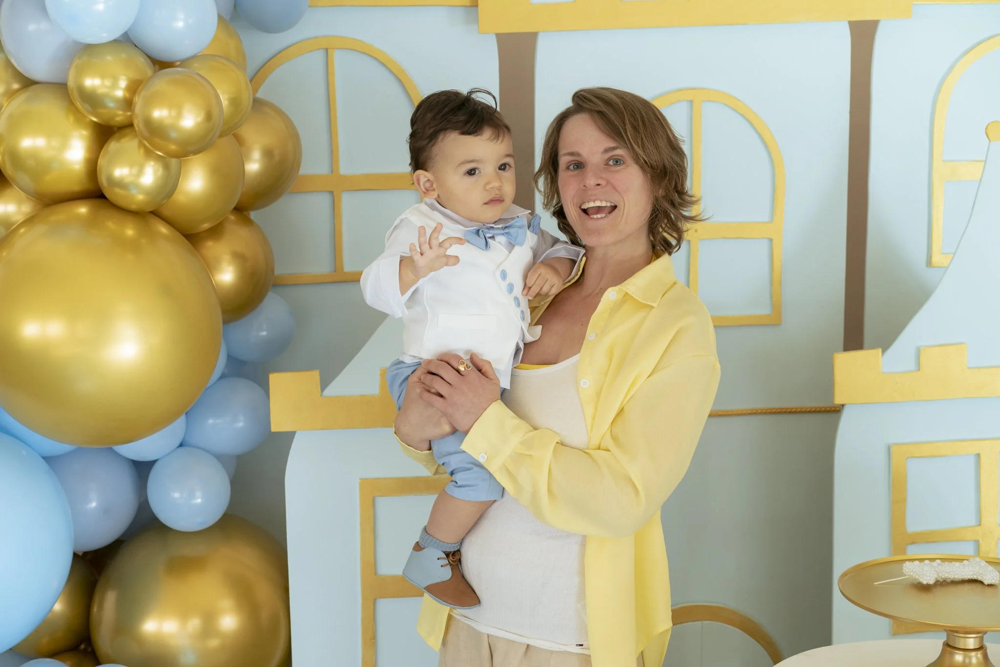 Babyborrel met blauw en goud ballondecor tijdens eerste verjaardag – evenement fotografie Gent, spontane familieportretten.