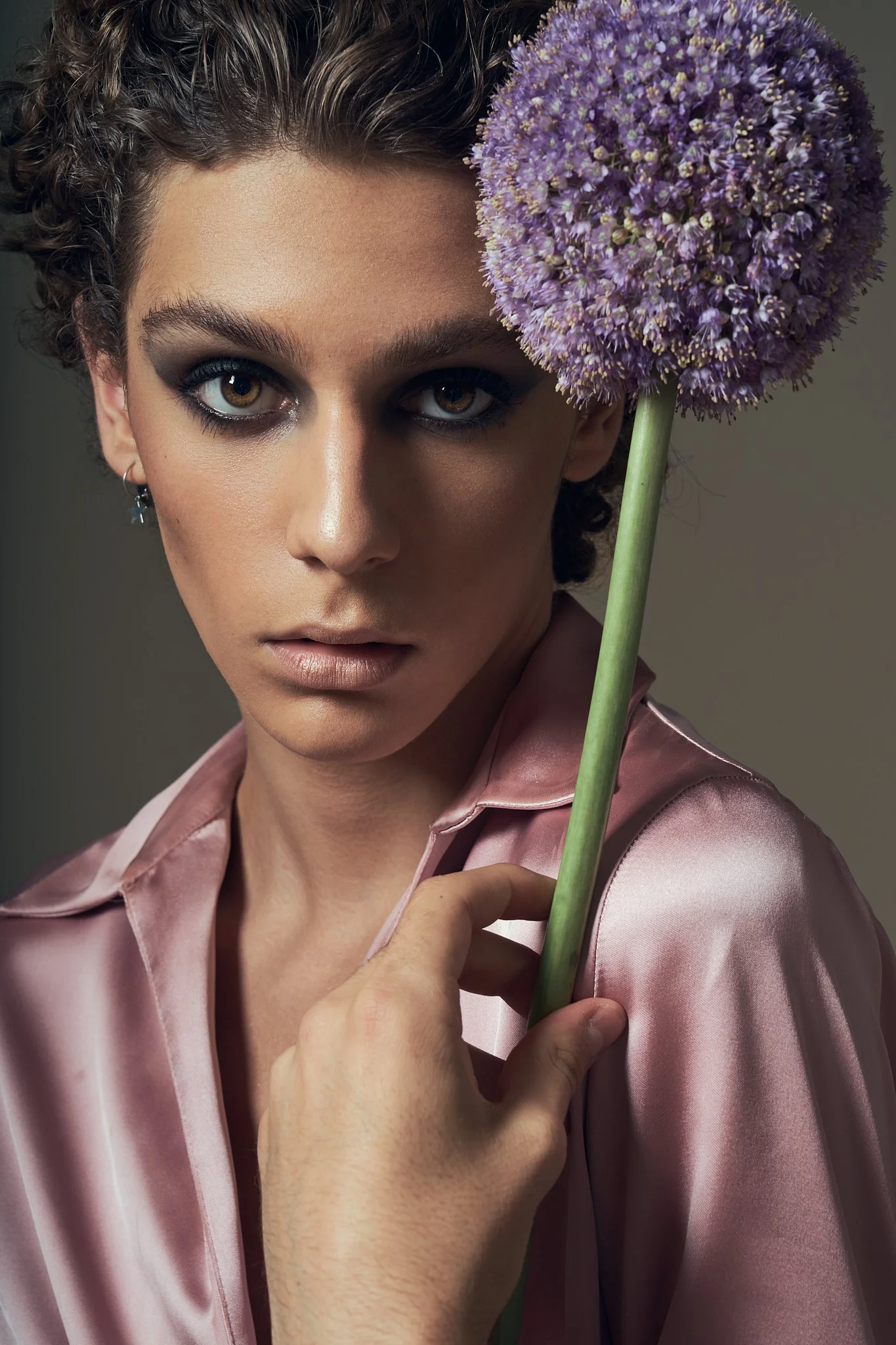 Androgynous beauty portrait with a model holding a large purple allium flower. Silky textures and subtle gender fluidity define this editorial by Flemish photographer Simon Rogghe.