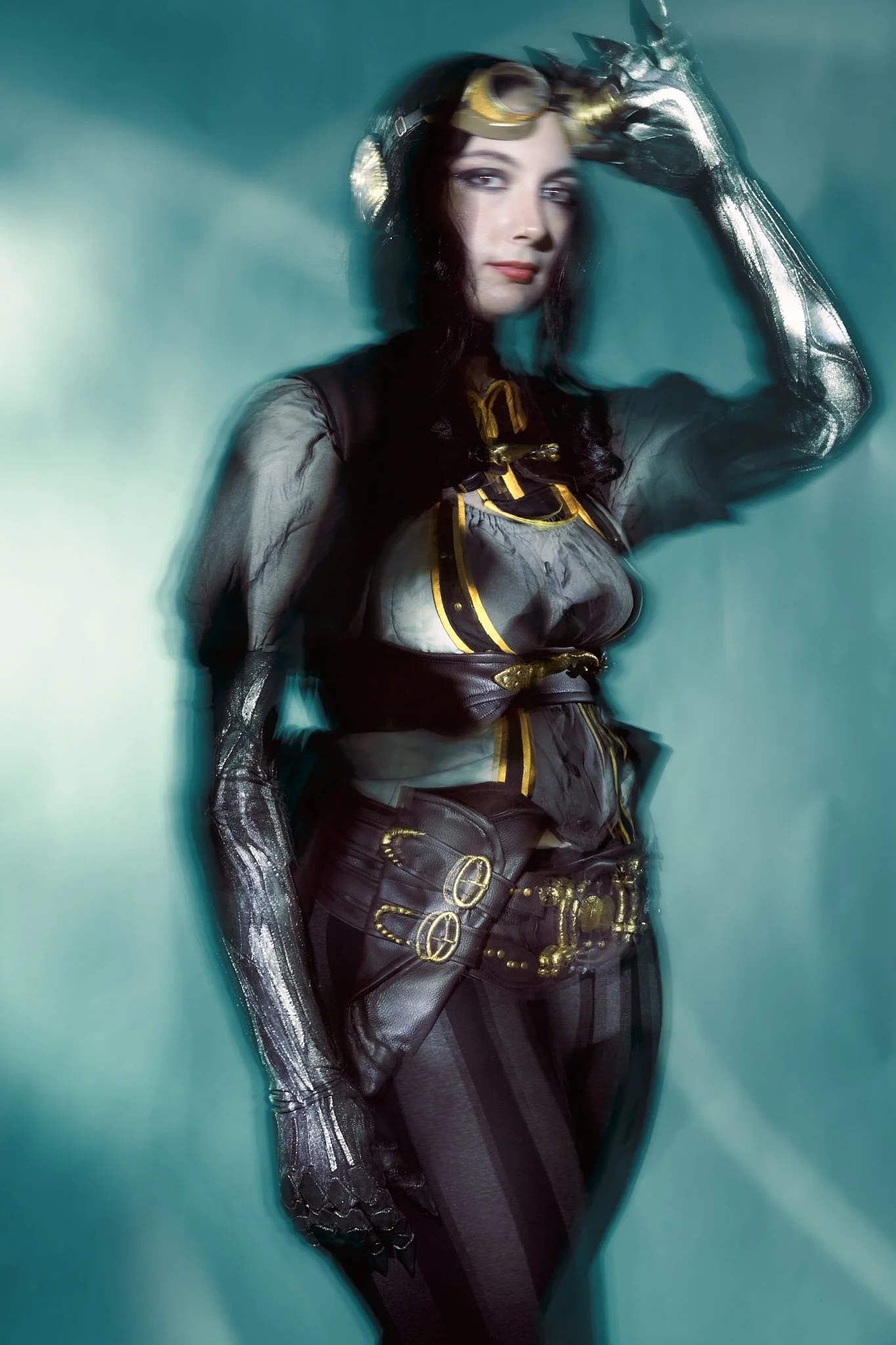 Lady Mechanika cosplay portrait — woman in steampunk striped leggings, leather utility belt and silver mechanical arm, holding a brass-and-silver rifle, photographed with light-painting on teal. Editorial cosplay photography by Simon Rogghe.