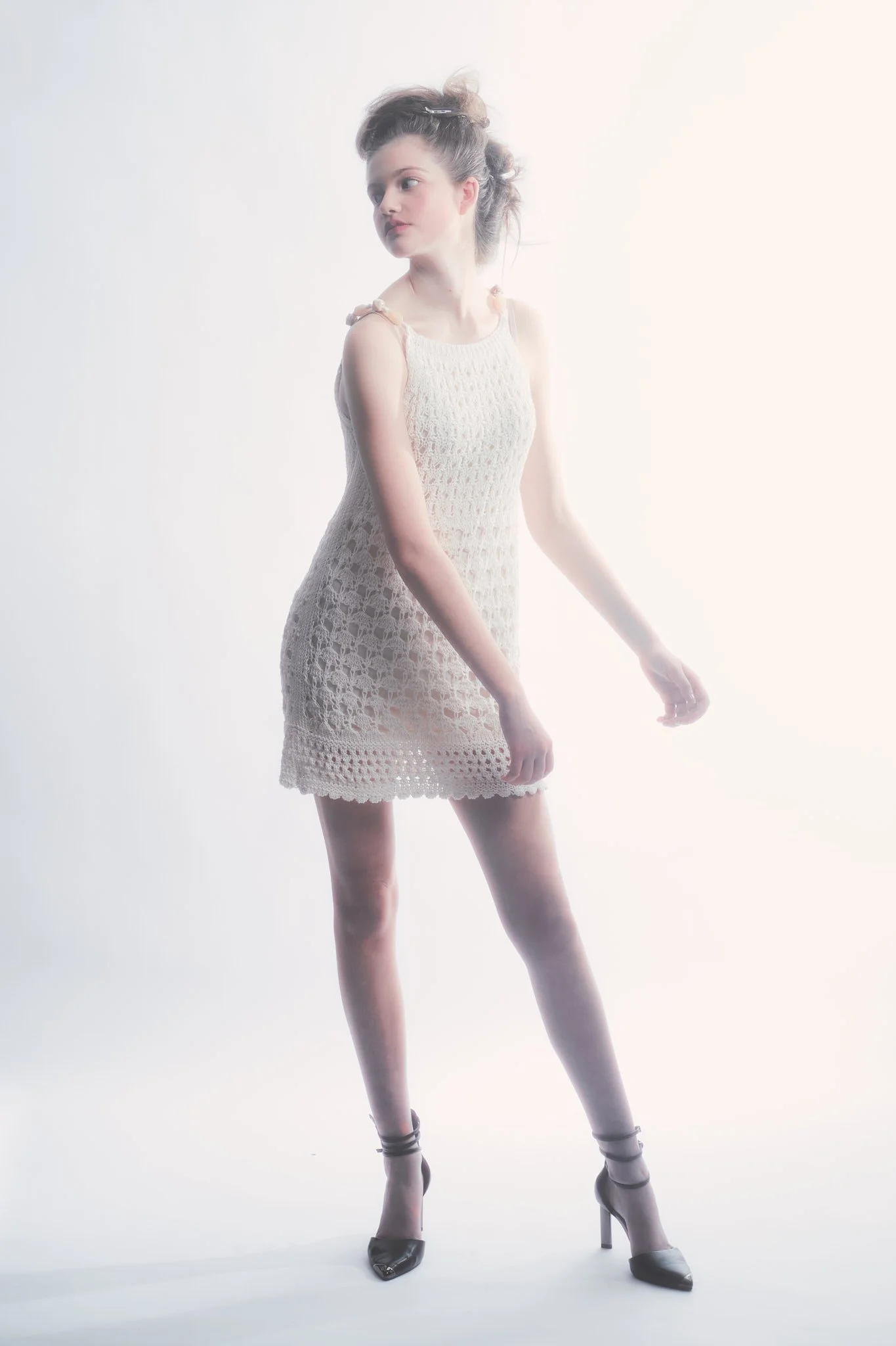 High-key editorial fashion image of model in crochet dress with swaying arms, by Ghent-based fashion photographer Simon Rogghe.