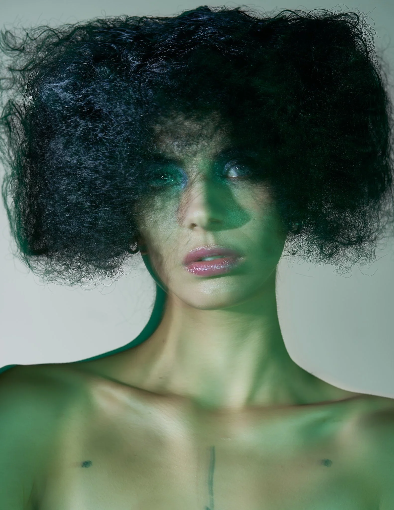 Tight close-up beauty shot focusing on glowing skin, subtle eye shadow, and glossy lips bathed in a green gel studio light.⁠