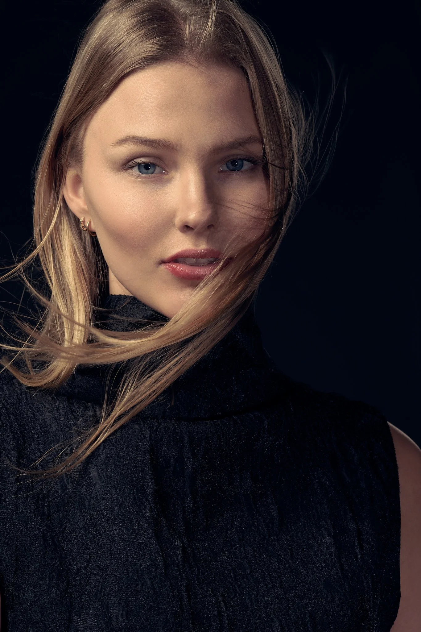 Natuurlijk model portfolio portret van jonge vrouw met los haar in zacht licht, geschikt voor aanmelding bij modellenbureau.