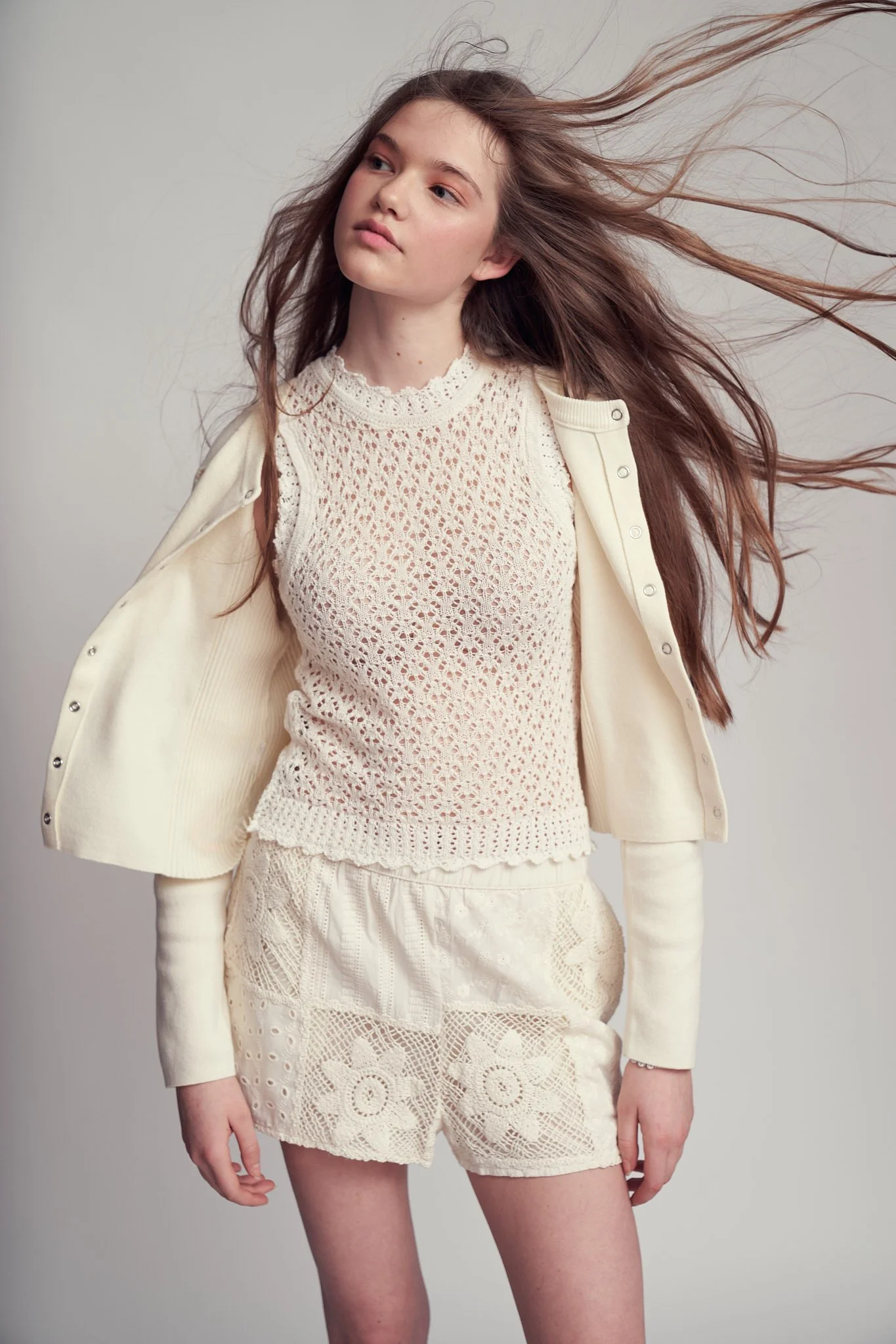 High-fashion studio shot of a young model in a cream lace top and matching shorts, hair flowing in motion for a modern, airy look—contemporary editorial photography by a Ghent-based Belgian fashion photographer.