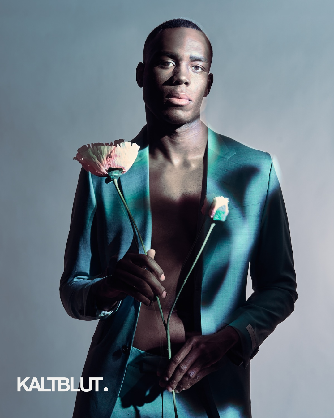 Editorial fashion portrait of Black male model in green suit holding flowers, minimalist studio lighting, modern high-fashion photography