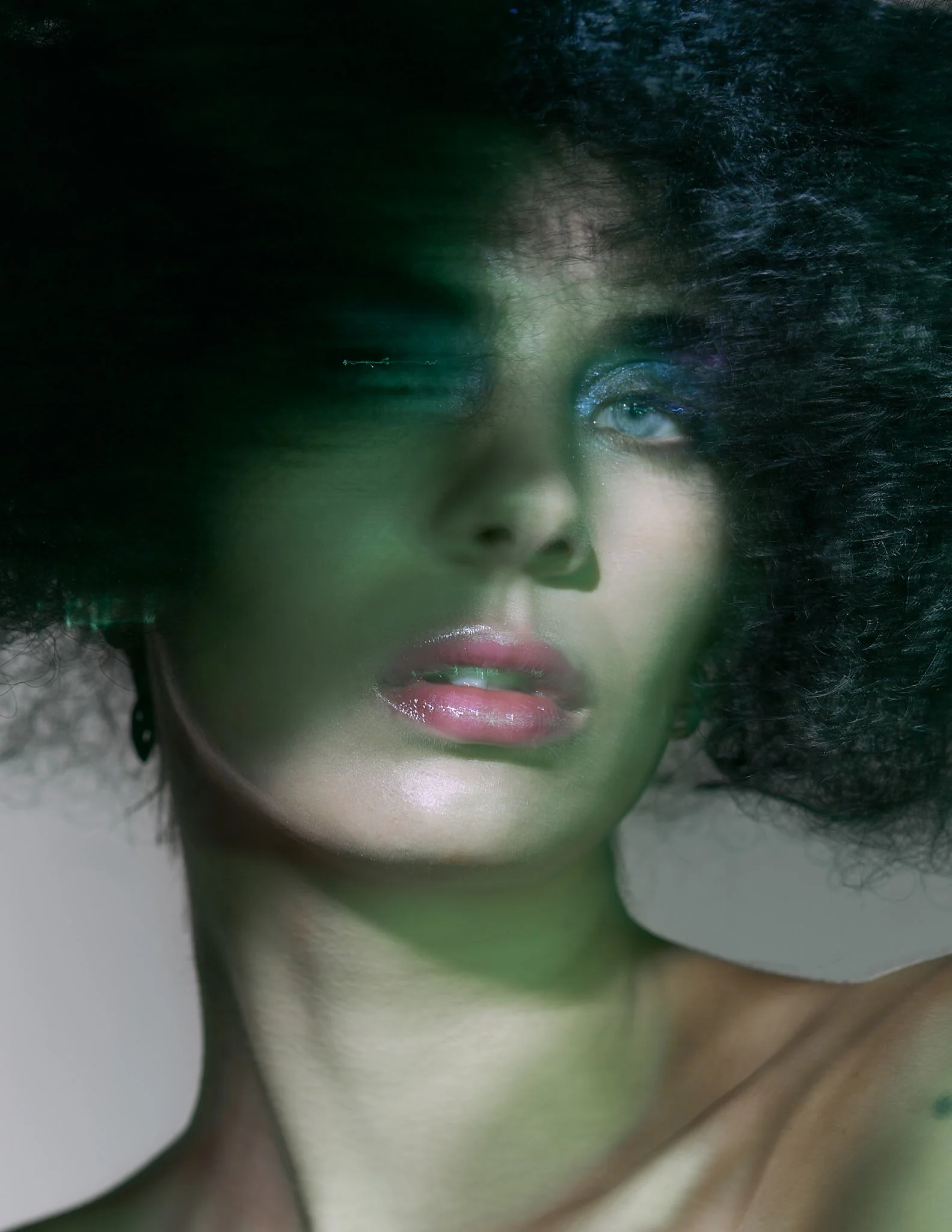 High-concept beauty portrait featuring a model with a massive, textured black bob wig under moody green lighting tones.⁠