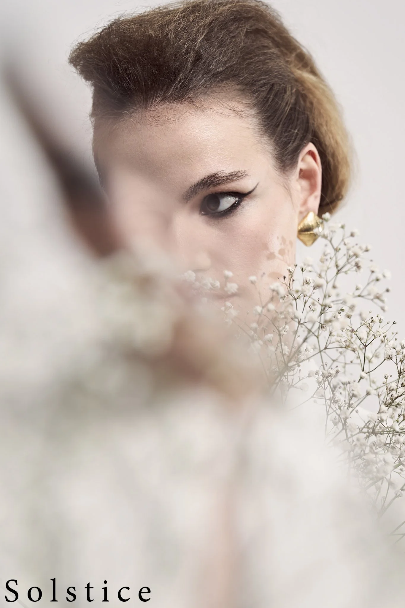Fashion portrait of female model partially obscured by soft-focus baby’s breath flowers, editorial photography by Simon Rogghe, Belgian fashion photographer based in Ghent, published in Solstice Magazine