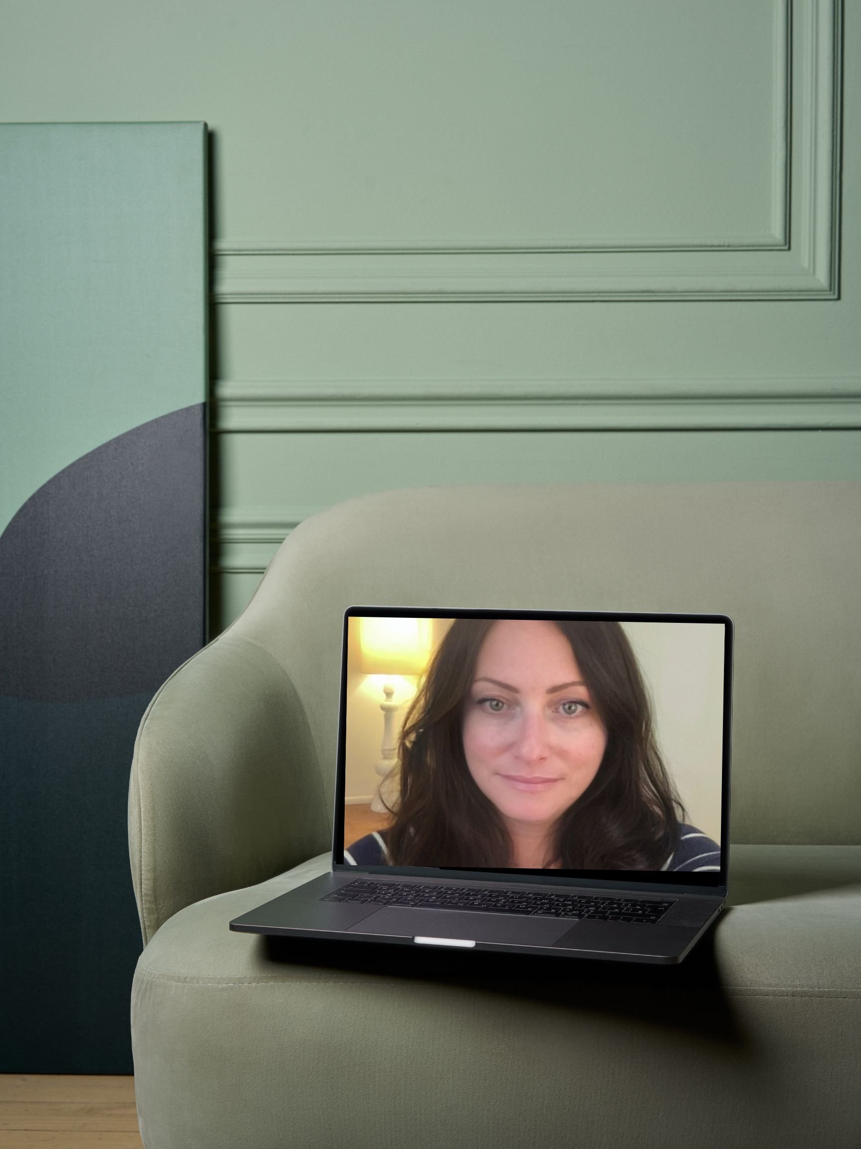 A laptop with a woman's face on the screen, placed on a green couch in a room with green walls and decorative molding. Accelerated healing for adults who want fast results—not just talk. Online therapy- Laura Geftman, LCSW throughout PA, NY, NJ, FL.