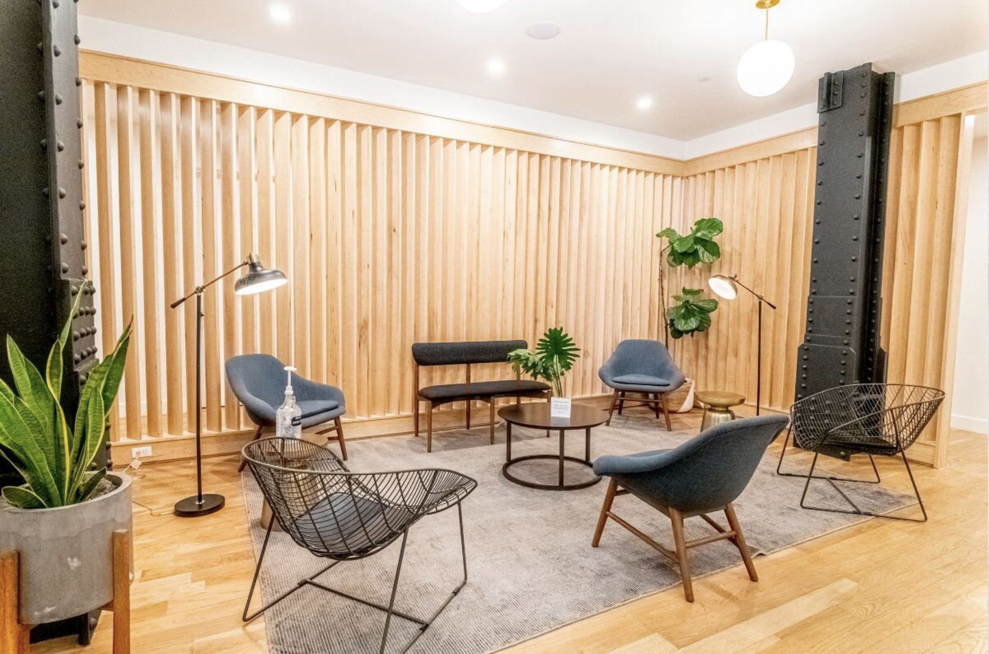 Modern seating area with six chairs, a coffee table, plants, lamps, and a wooden wall in the waiting room. In-person Accelerated Resolution Therapy in New York City with Laura Geftman, LCSW.