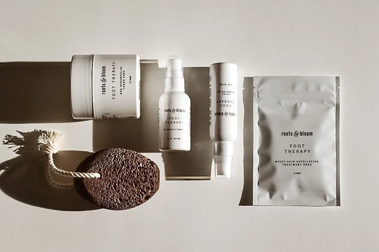 A collection of Roots and Bloom’s foot therapy products and a pumice stone designed to cure cracked and dry feet. roots and bloom foot therapy sole products skincare regimen new years resolutions 2021 cure cracked feet and dry heels self care treat dry skin pedicure products #rootsandbloom #skincareproducts #curecrackedfeet #dryheels #pedicure #selfcare #newyearsresolutions #2021 #soleproducts #foottherapy #skincareregimen