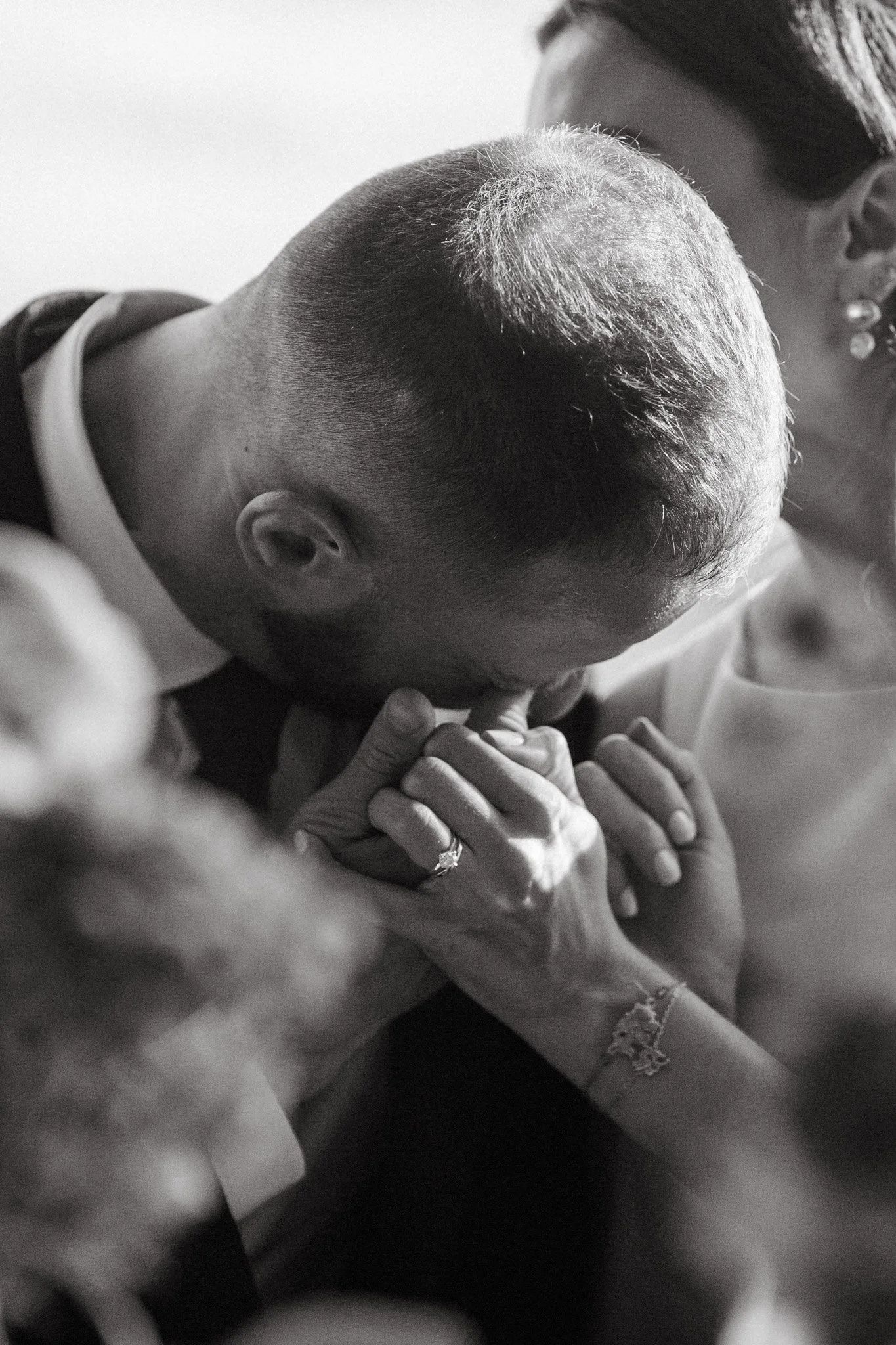 Man kissing woman's hand, wearing an engagement ring, black and white photo