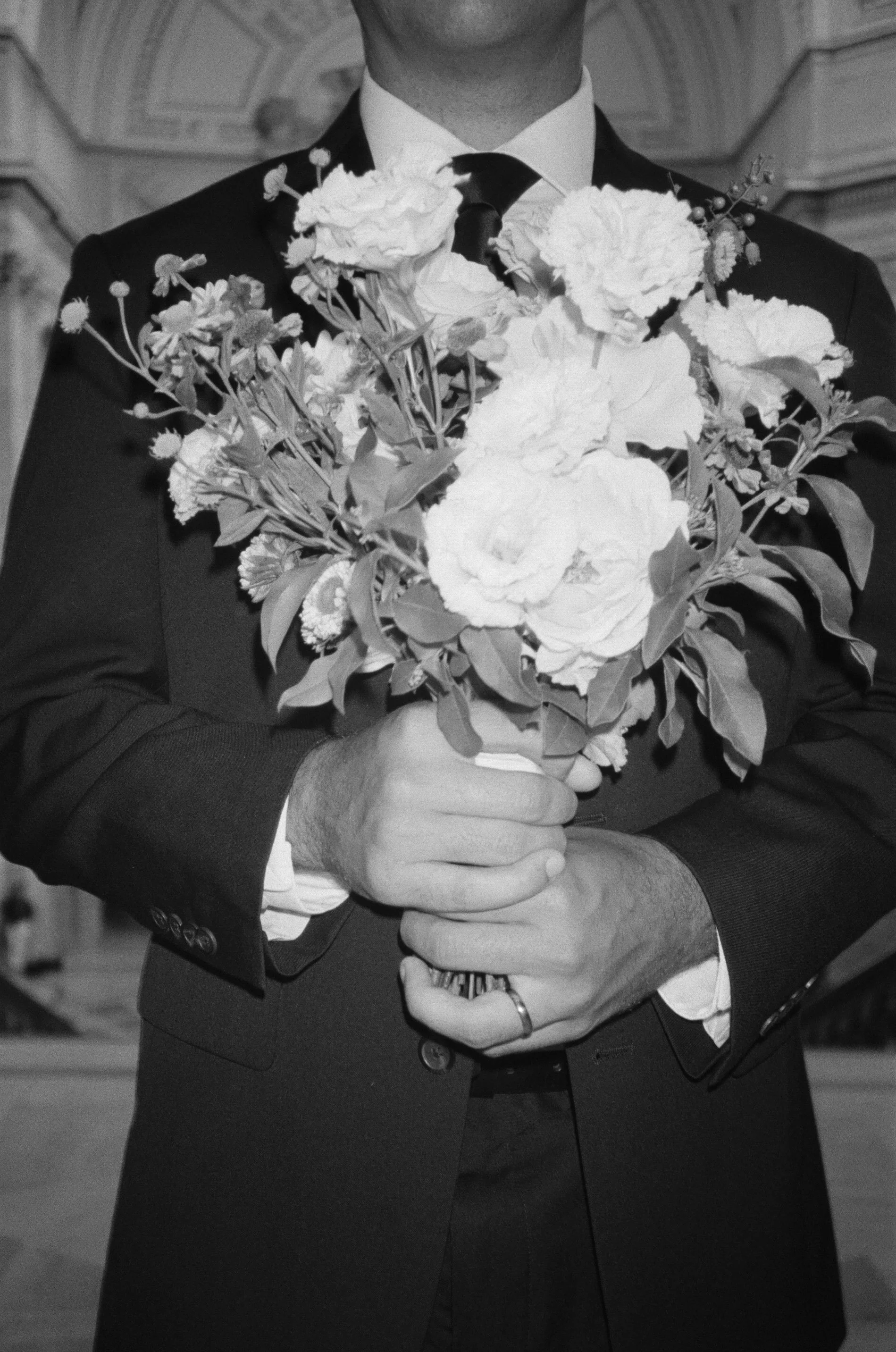 Person in suit holding a bouquet of flowers