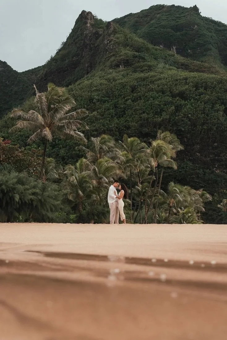 proposal at tunnels beach with green mountains behind the couple