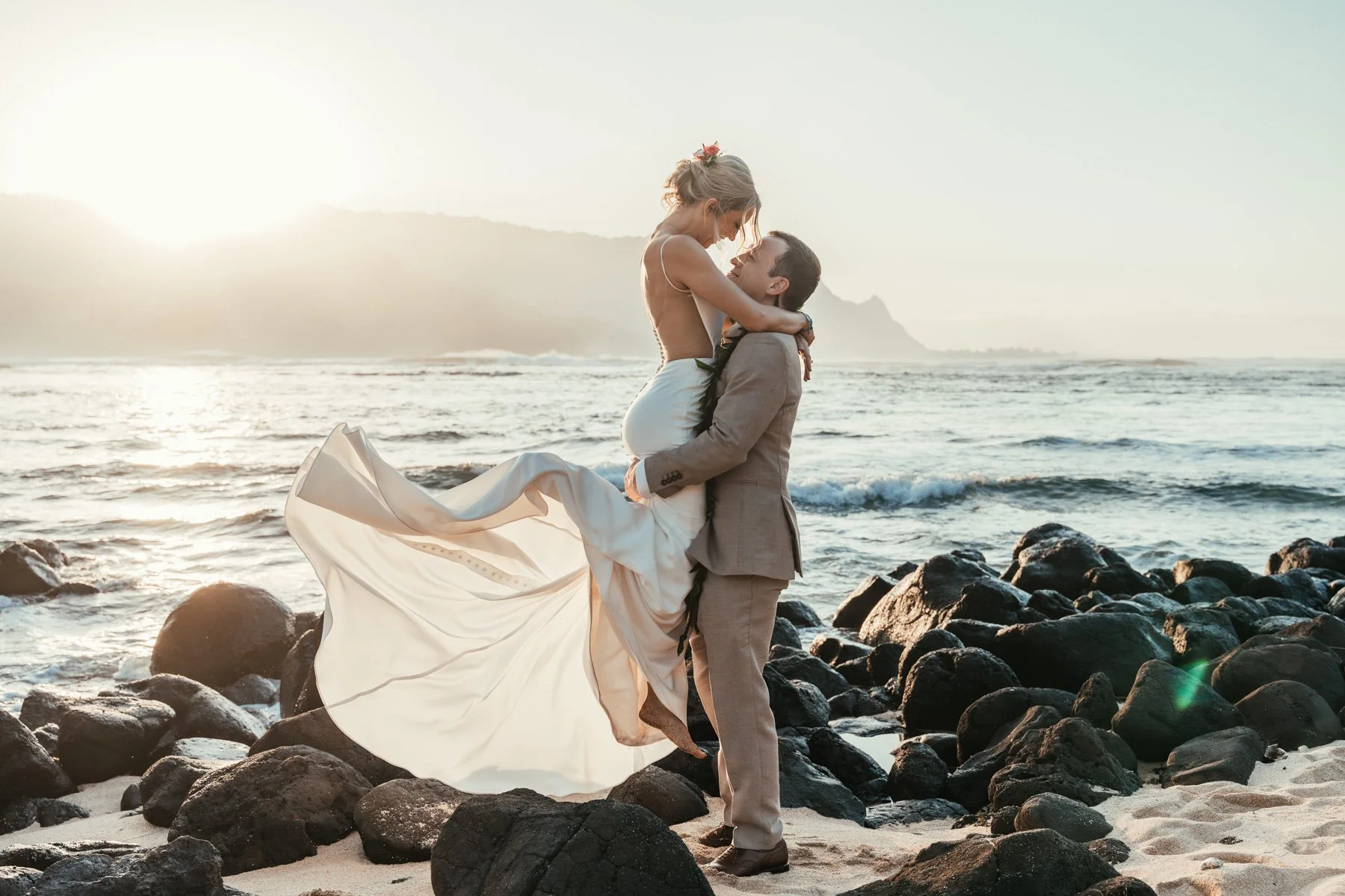 groom picks up bride on sand during sunset at 1 Hotel Hanalei