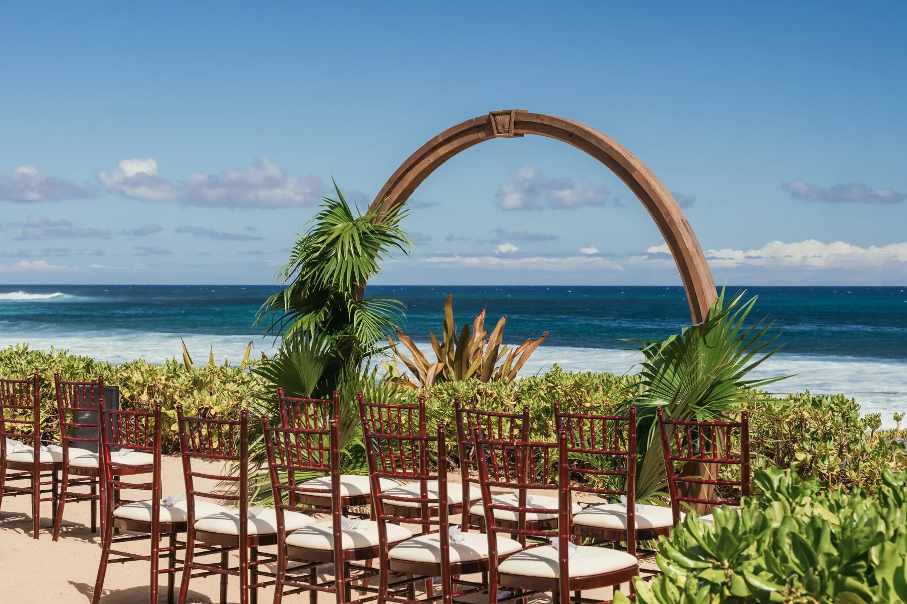 Wooden ceremony arch and rows of chairs overlooking the ocean at the Grand Hyatt Kauai Resort in Poipu, Kauai wedding ceremony setup