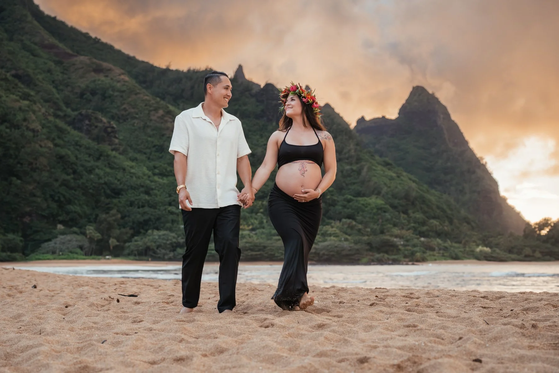 Maternity photos of expecting couple walking in sand
