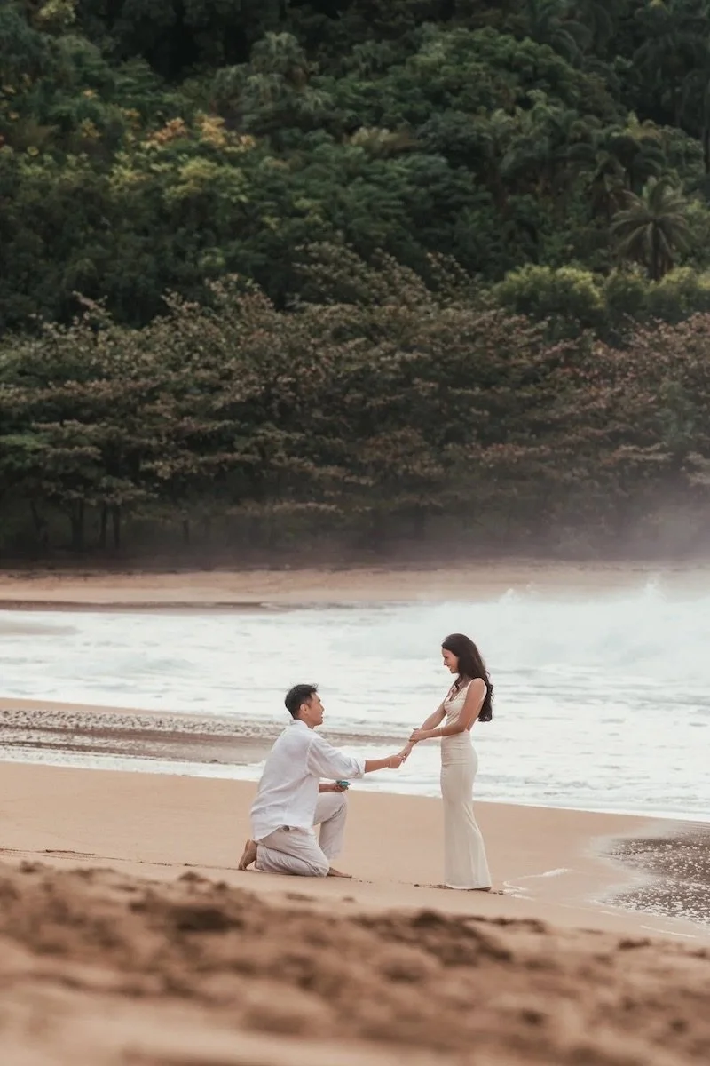 man on one knee in the sand proposing at tunnels beach