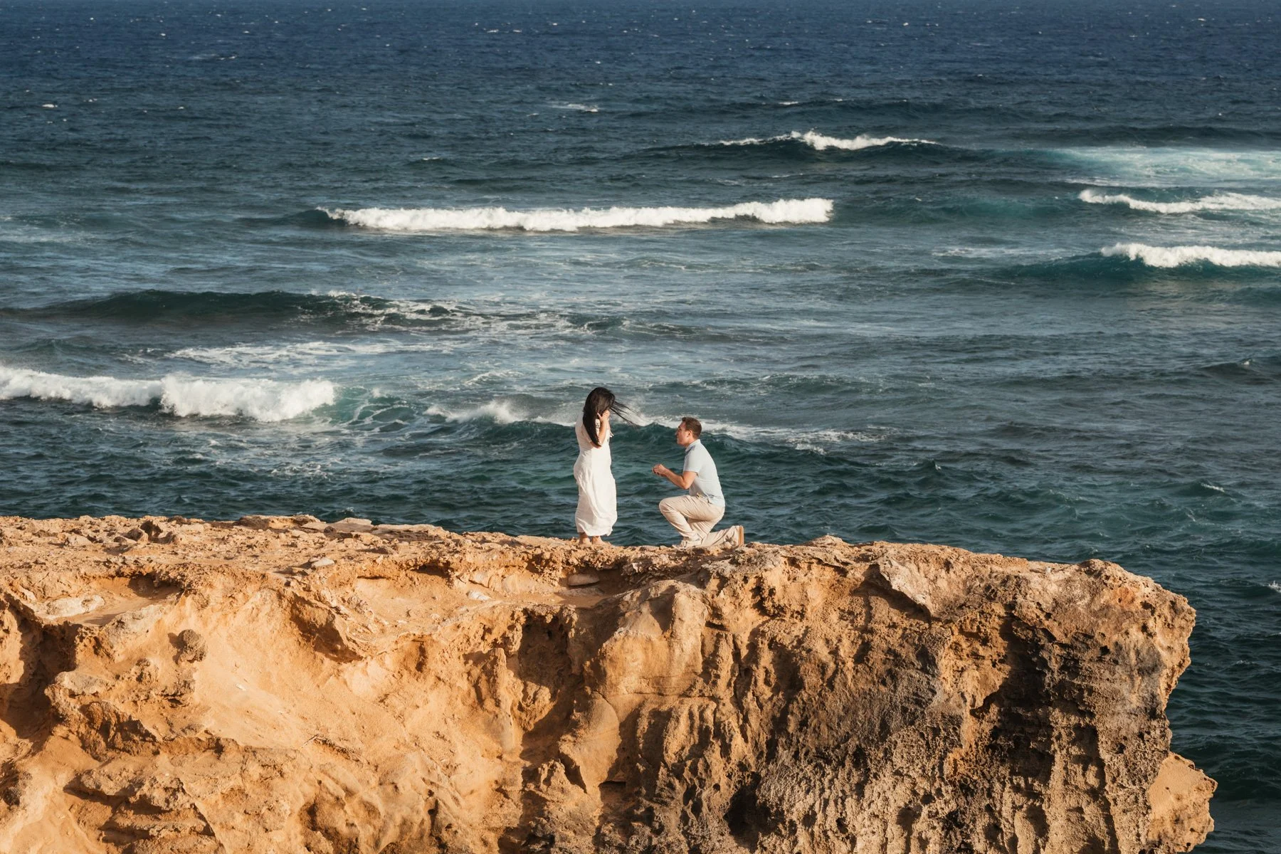 man proposing to fiance on cliff by Shipwreck Beach, Kauai