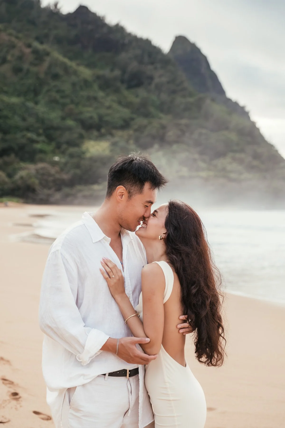 Couple embraces after proposal along beach on Kauai