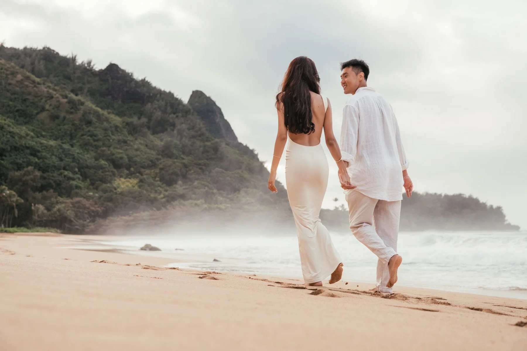 couple walking down beach in Kauai