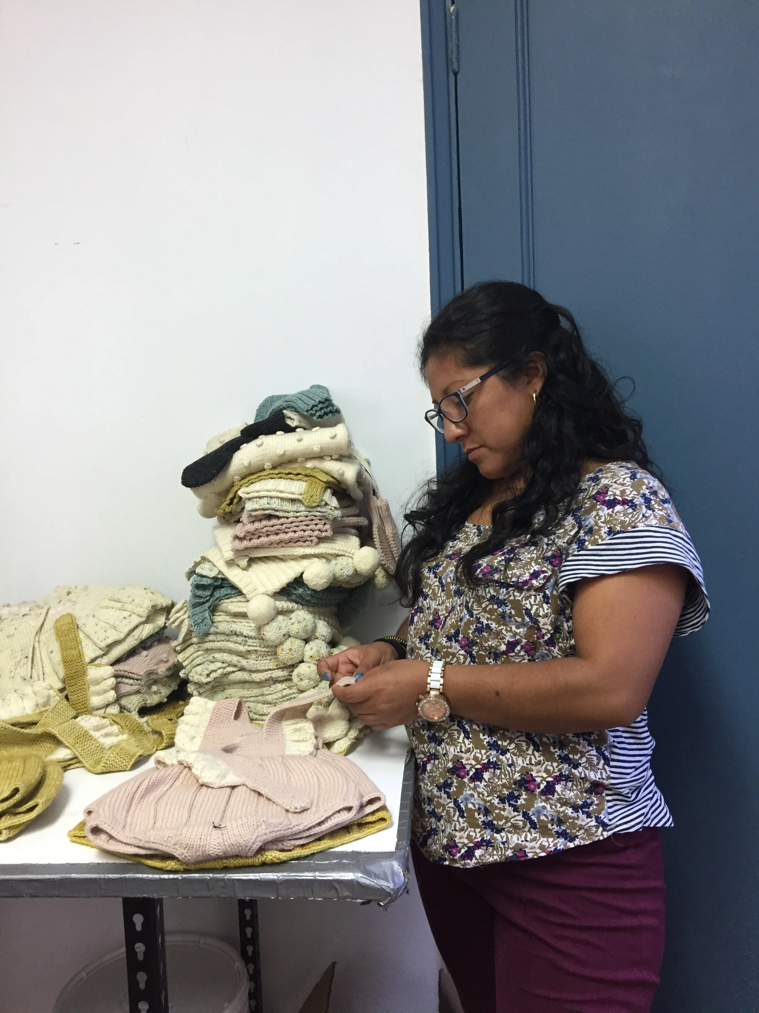 One of our lead knitters, Yanet, reviewing our FW17 pre-production and making sure our buttons are staying snug.