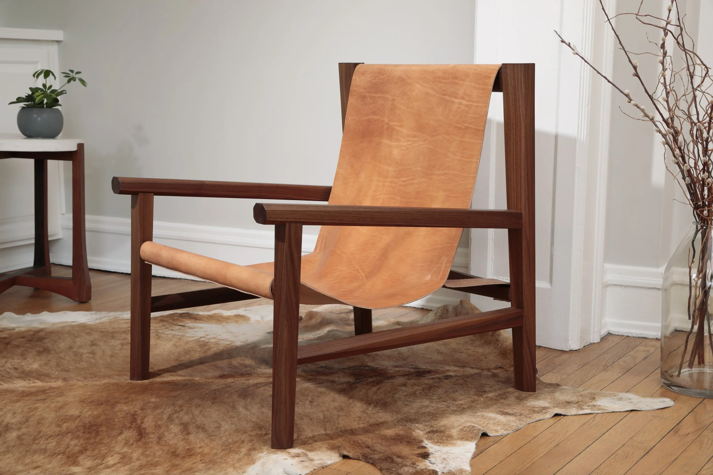 Combining the warmth of wood and the luxury of leather, this sling chair is the perfect place to spend an evening of relaxation. A collaboration between Alicia Dietz Studios and Awl Snap Leather, both women-owned business in Richmond, VA. A low and d