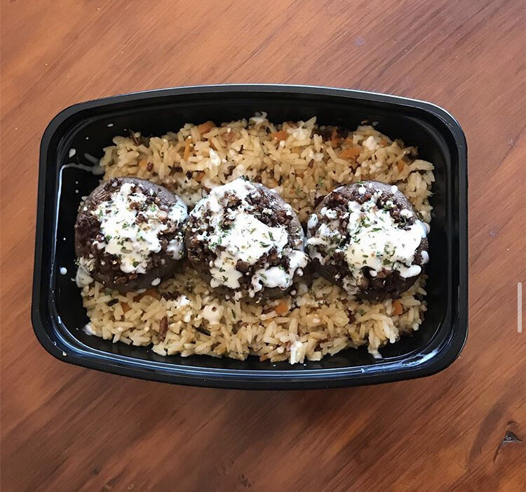 Stuffed Mushrooms with meatless crumble, topped with vegan cheese & parsley, served on a bed of wild rice