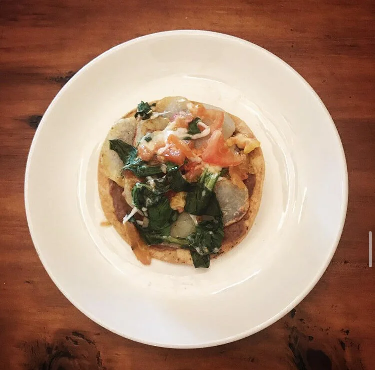 Tostada, with vegetarian refried beans, potatoes, spinach, tomatoes, dairy free cheese