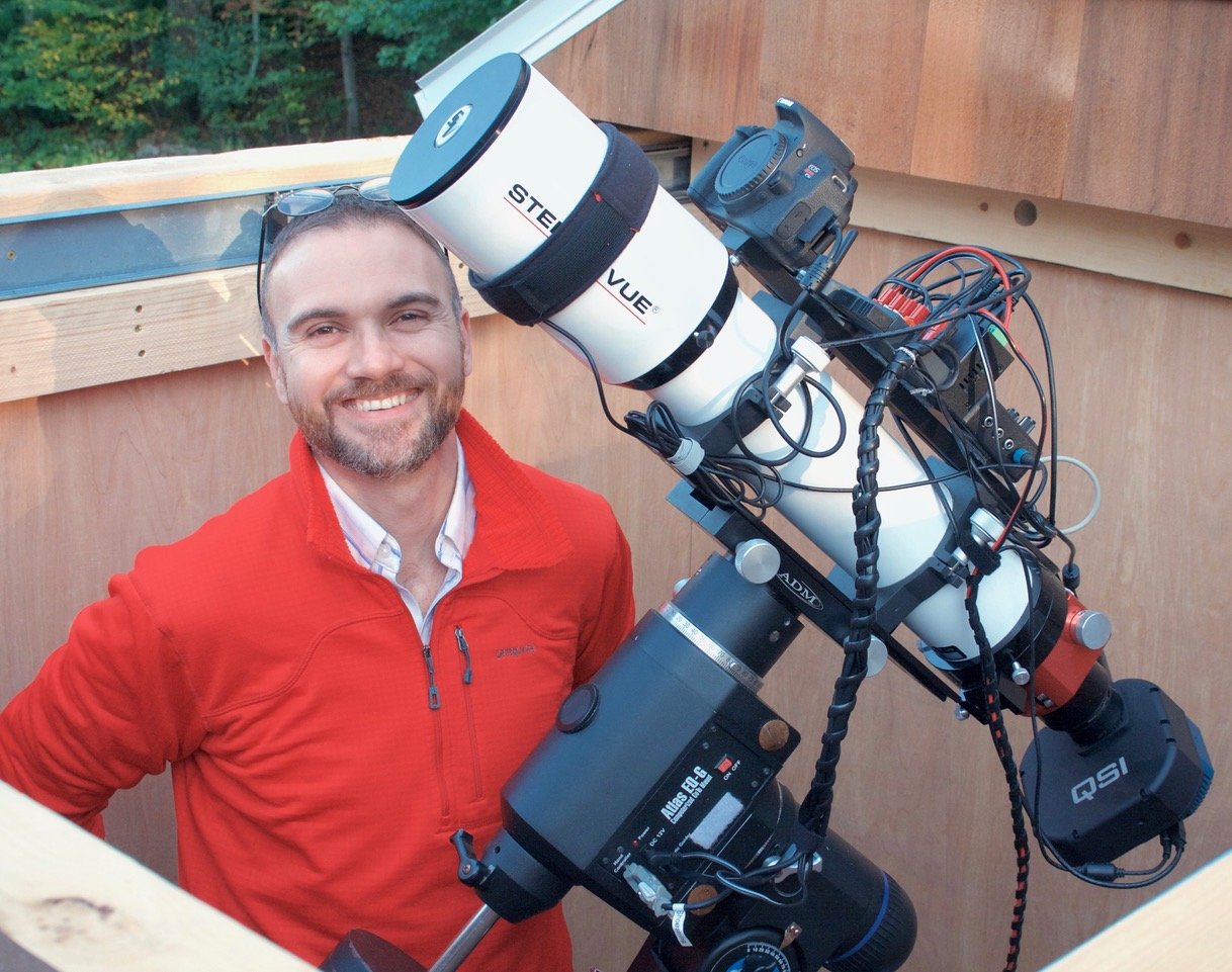 Destin Heilman smiling at camera with telescope