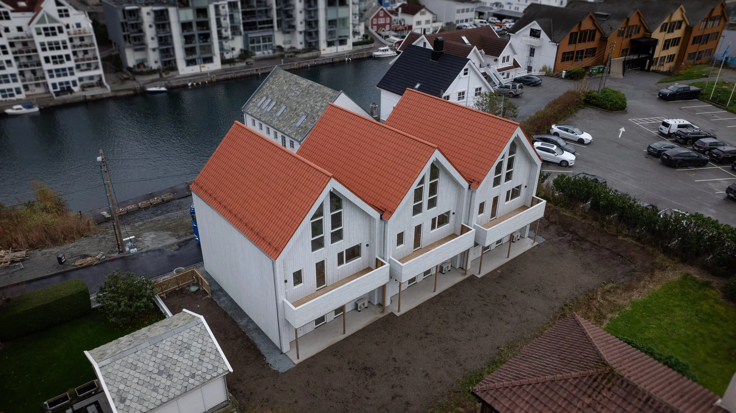 Tre hvite rekkehus med røde tak og store vinduer i Haugesund