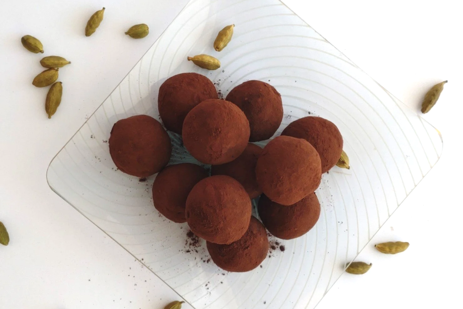 A pile of truffles rolled in cocoa powder on a glass plate