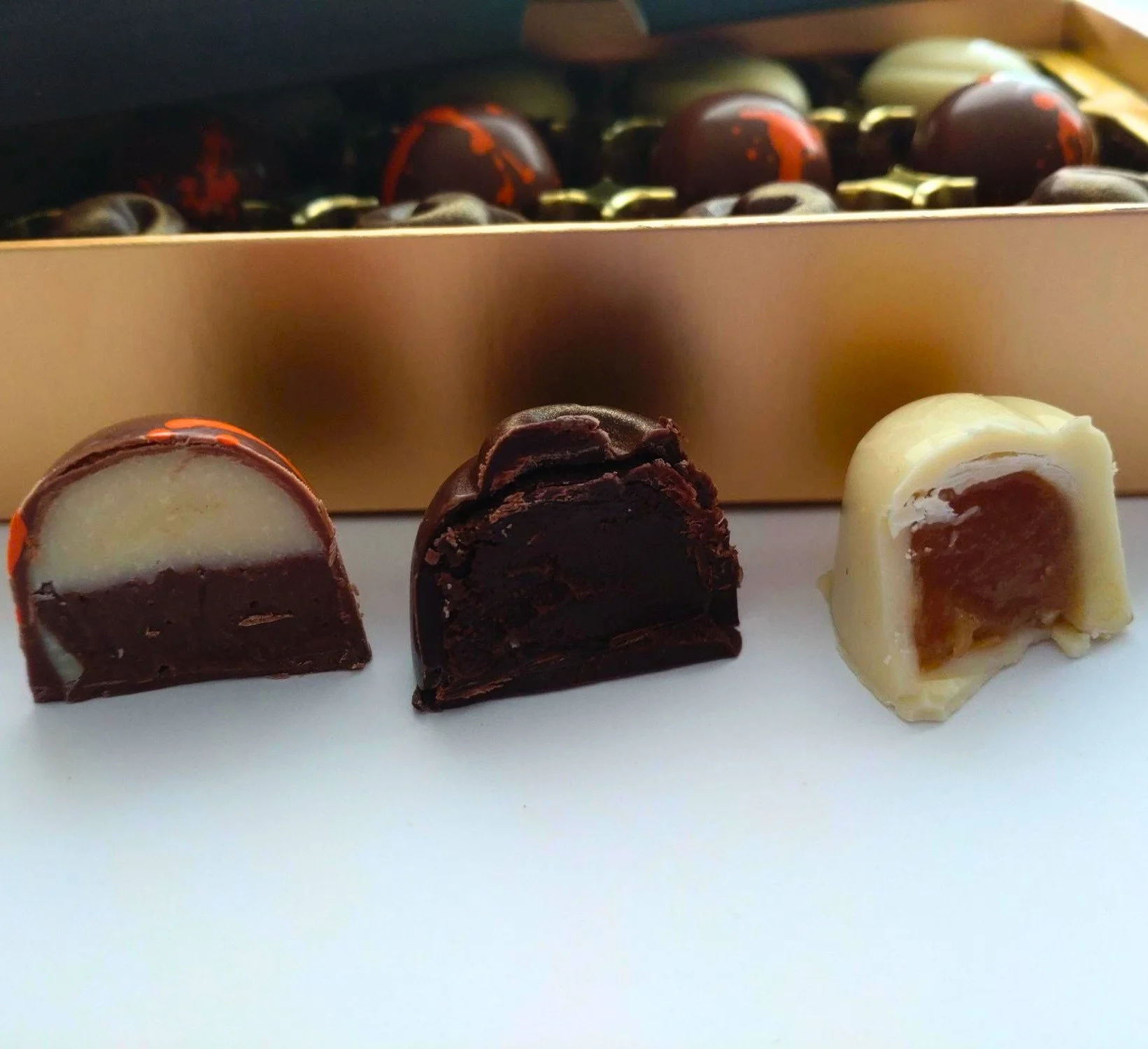Handmade Japanese-inspired chocolate collection by Truffle Witch, showing the centres of yuzu, matcha and ginger, and miso caramel chocolates.