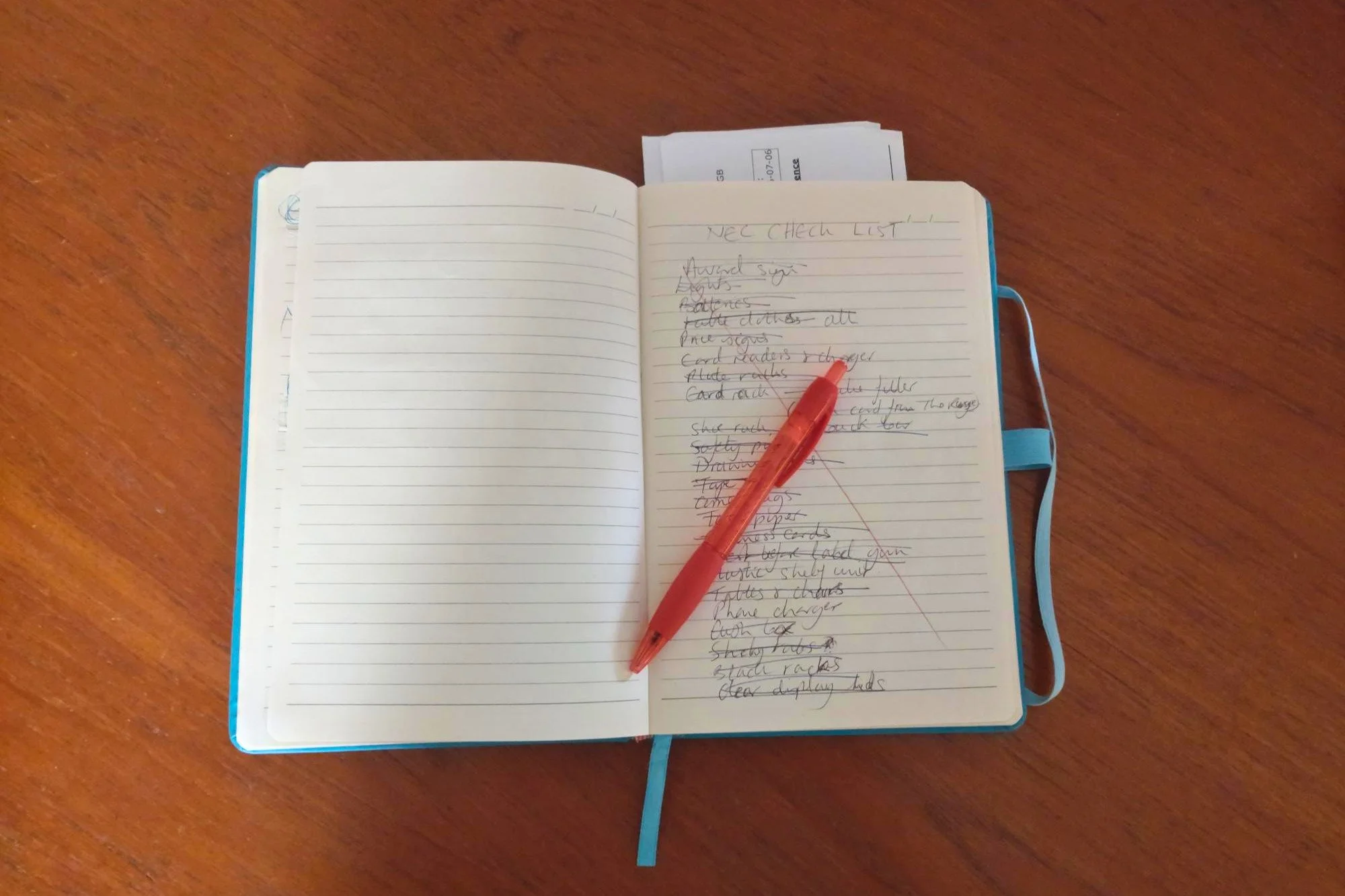 Open notebook on a dark wood surface, red pen across a page with scribbled notes