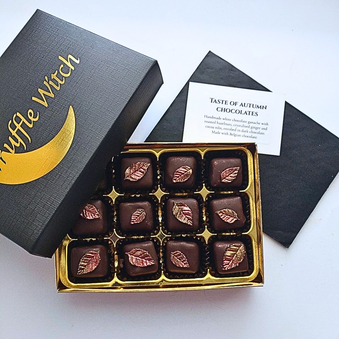 Truffle Witch black and gold gift box containing twelve Taste of Autumn dark chocolates with bronze leaf decorations, displayed alongside the printed chocolate menu.