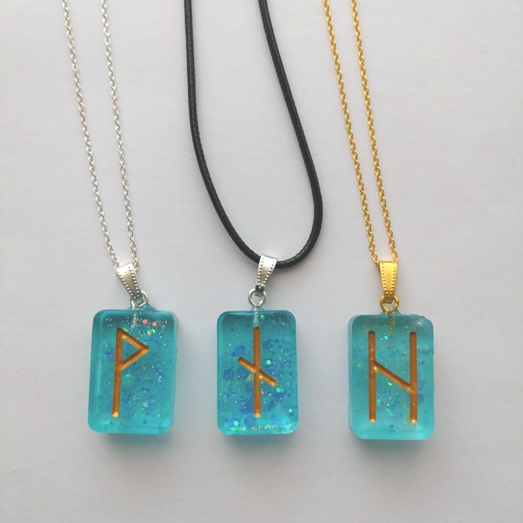 3 turquoise glitter rune stone pendants on a white background