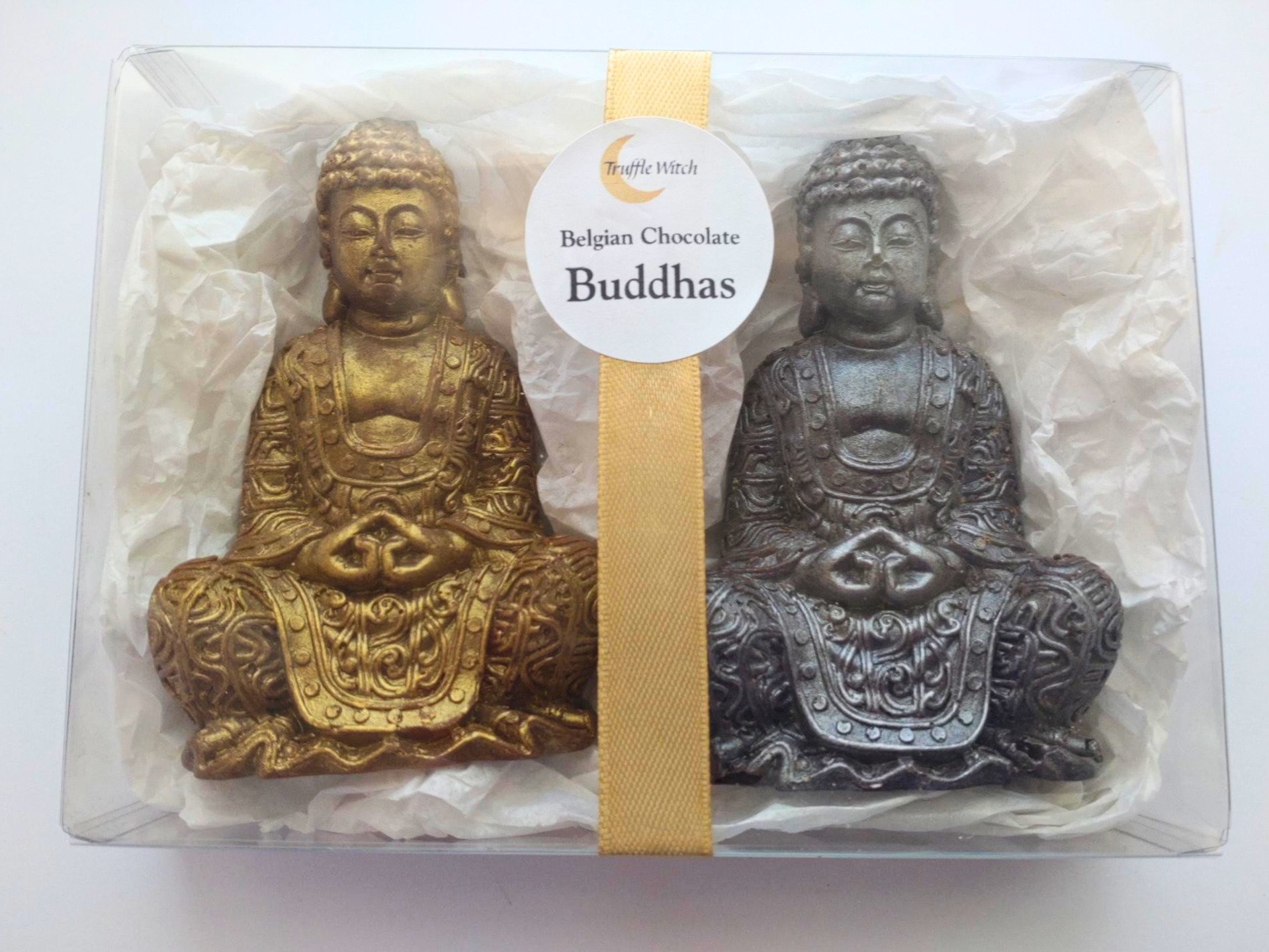 Gift box containing two handmade chocolate Buddha figures with white tissue and gold ribbon