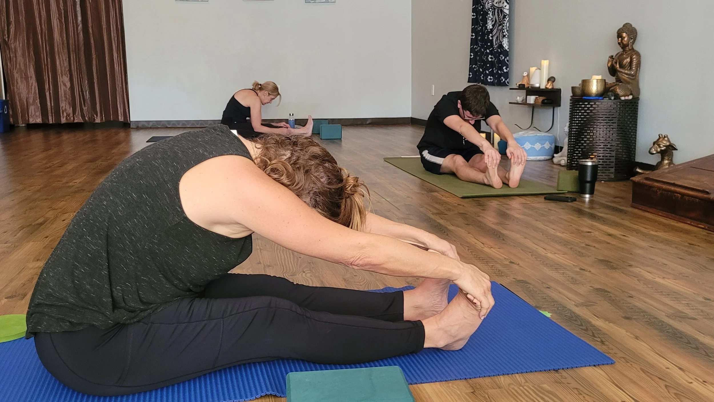 Student stretching in a seated forward fold during a beginner-friendly yoga class at Emerald Yoga Studio in Pembroke, MA, near Hanson