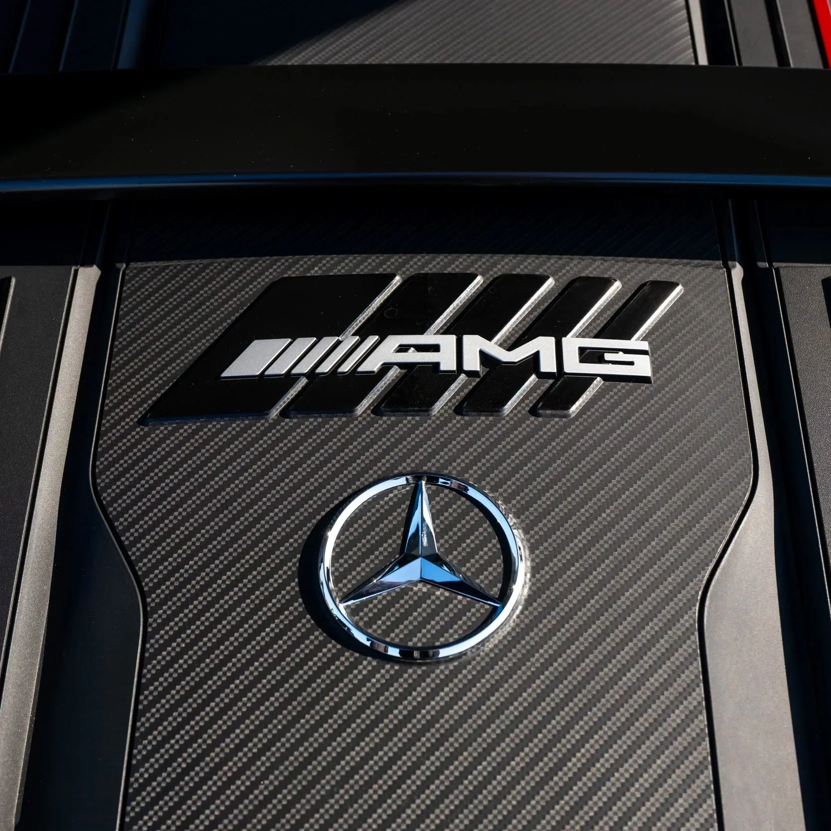 Close-up of a Mercedes-AMG engine cover with AMG and Mercedes-Benz logos.