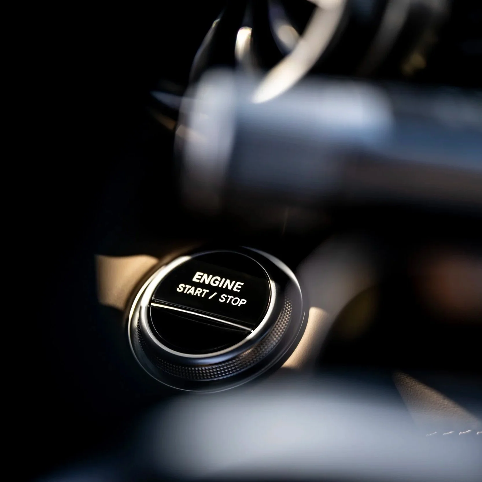 Close-up of a car's push-button start labeled 'ENGINE START / STOP'