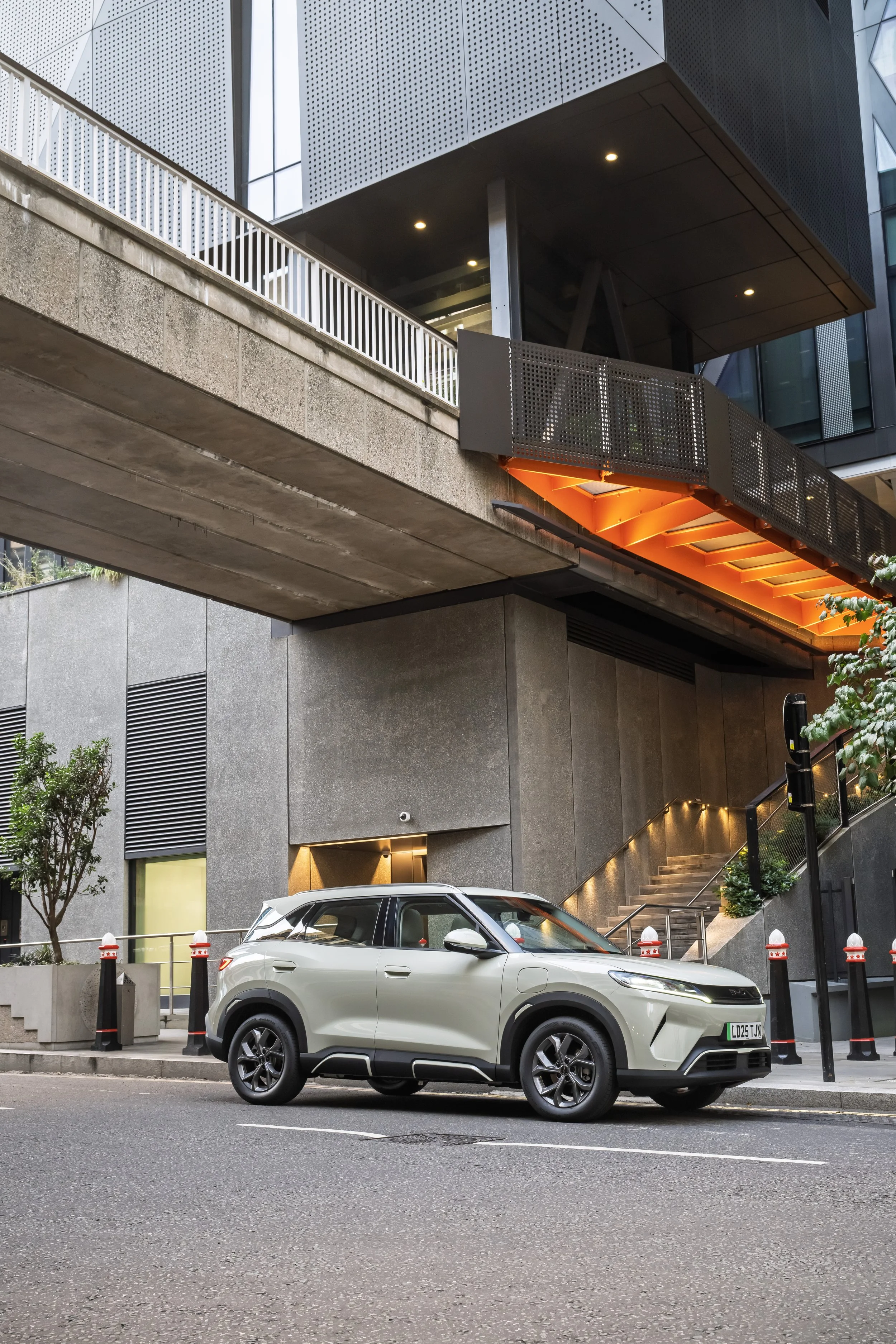 A white compact SUV parked on the street in front of a modern building with architectural details and lighting.