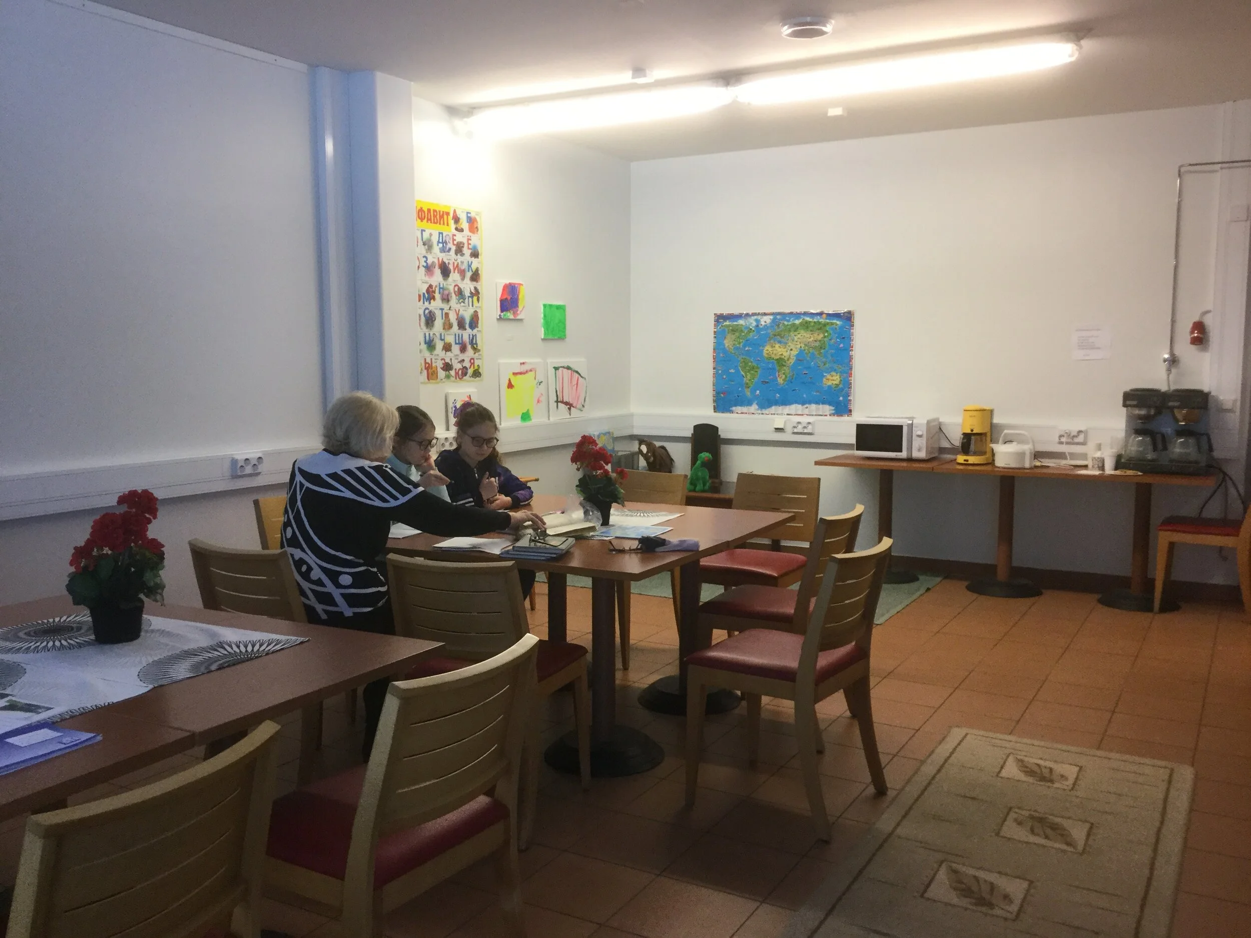 Kaksi lasta ja ohjaaja pöydän ääressä tekemässä koulutehtäviä.