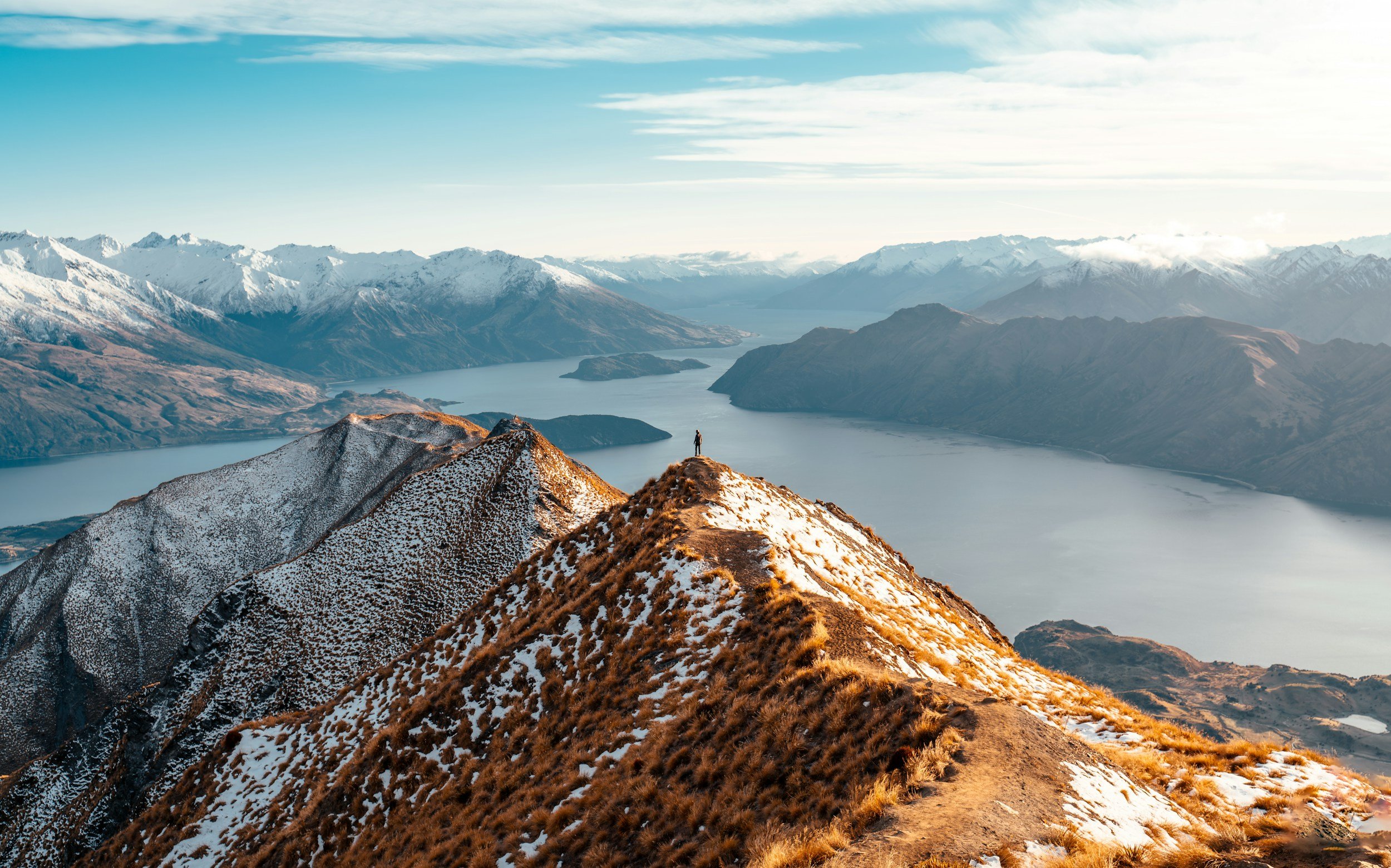 Hiker on a snowy mountain ridge overlooking a lake