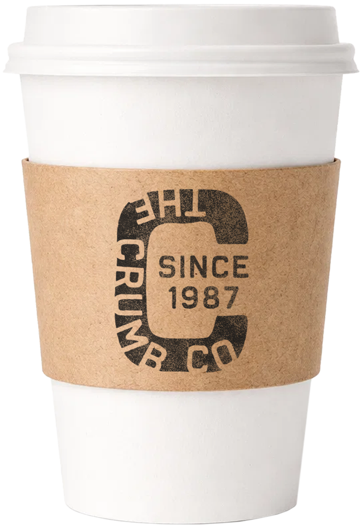 A white disposable coffee cup with a brown sleeve that has the logo 'The Crimmer Co' and the text 'Since 1987' on it.