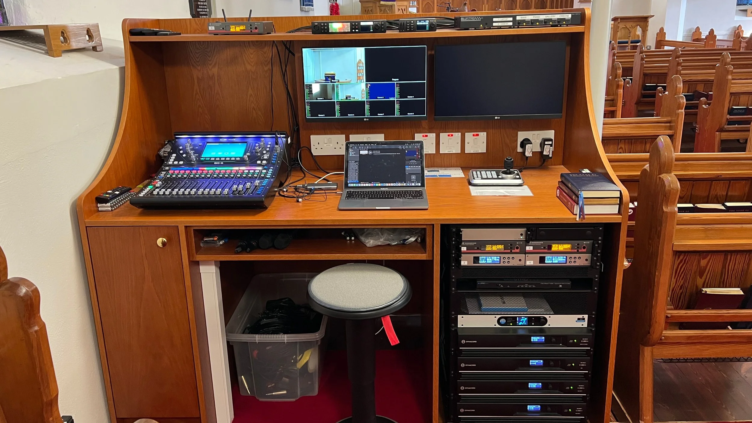 Sound desk set up at back of traditional church with laptop and screens