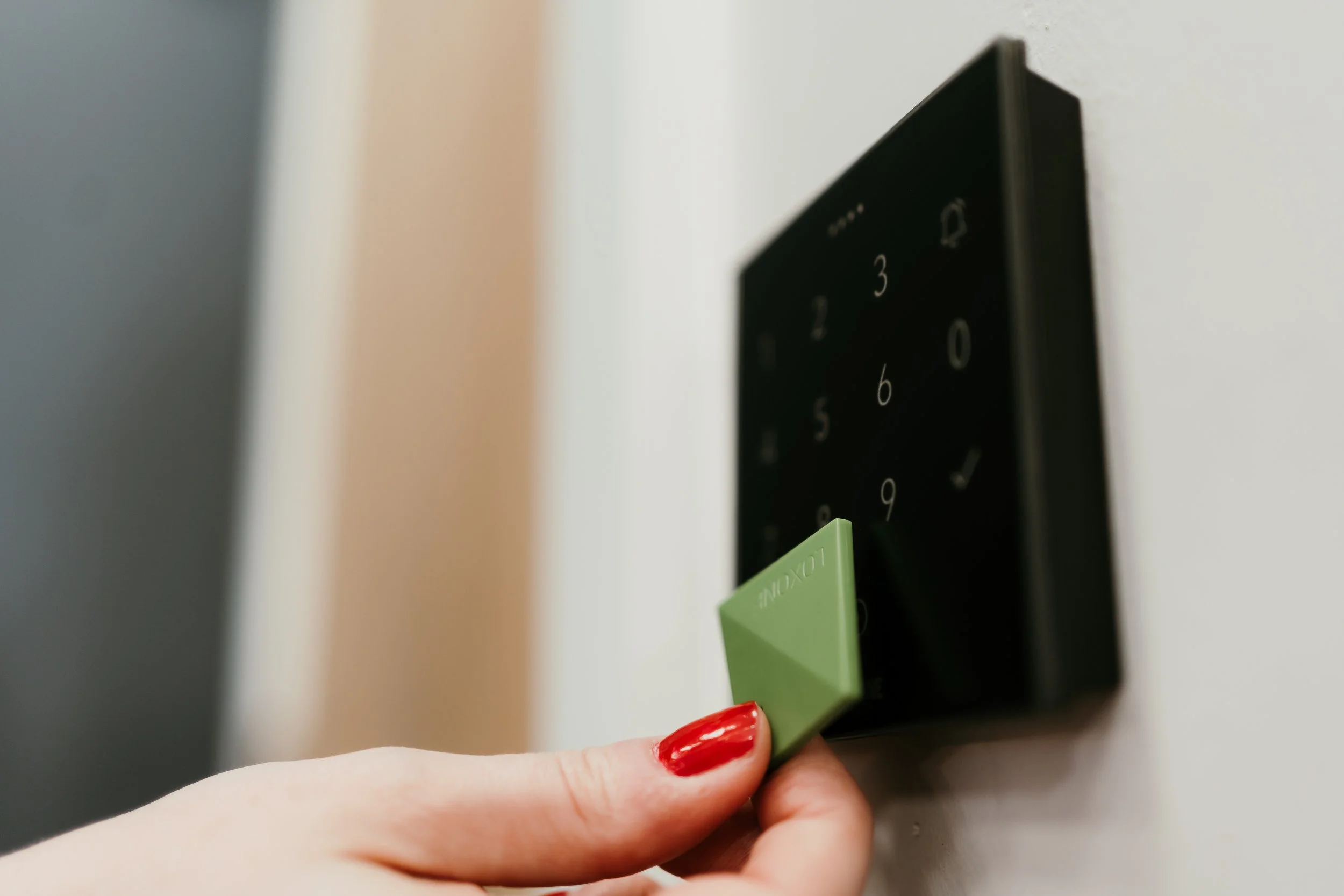 White modern video door entry system mounted on a wall with a numeric keypad and a camera.
